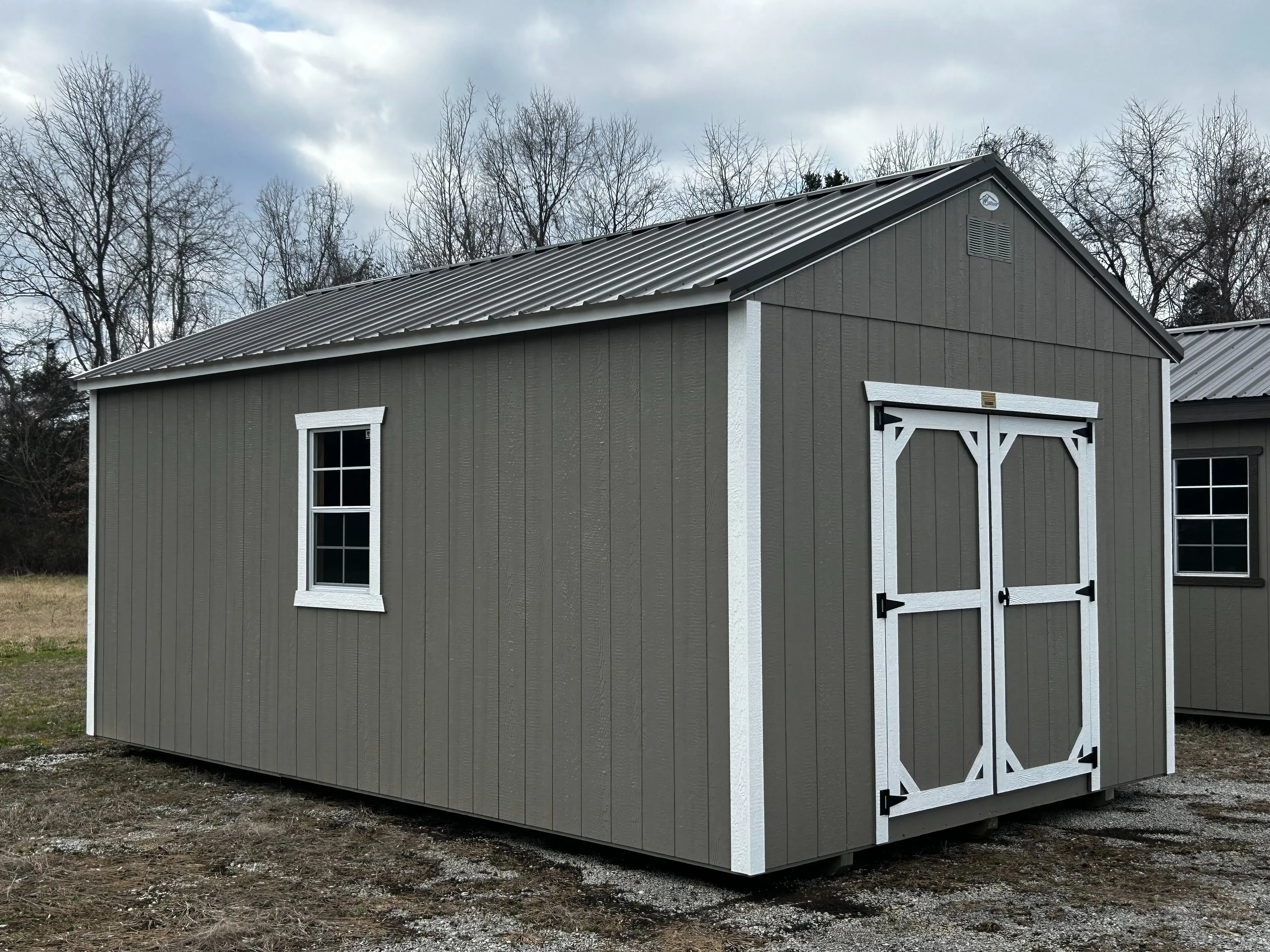 A 12x20 clay and bronze classic wooden utility shed from its left side.