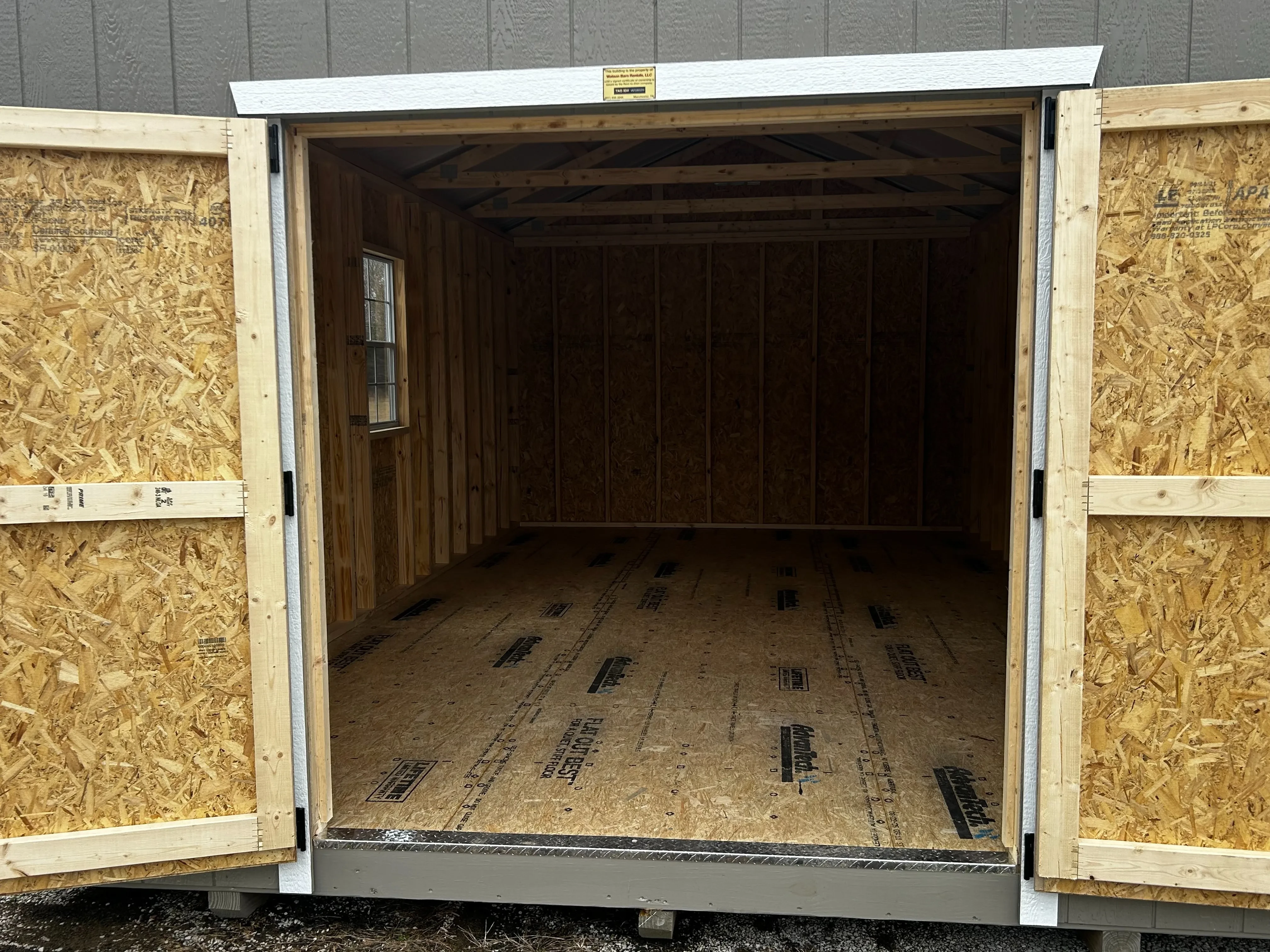 The interior of wooden shed showing the doors, diamond plate entry and slots of space.