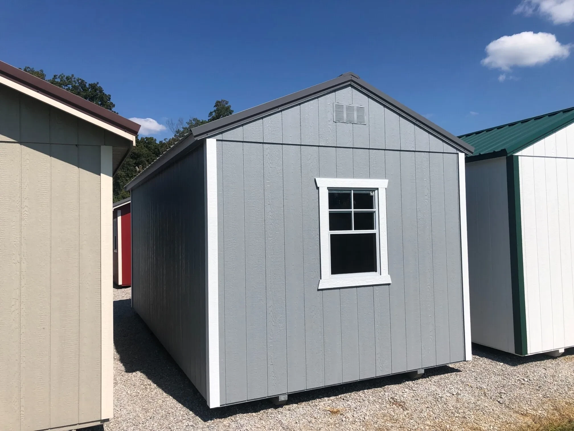 the back side view of a grey shed showing a window in the middle of the back wall