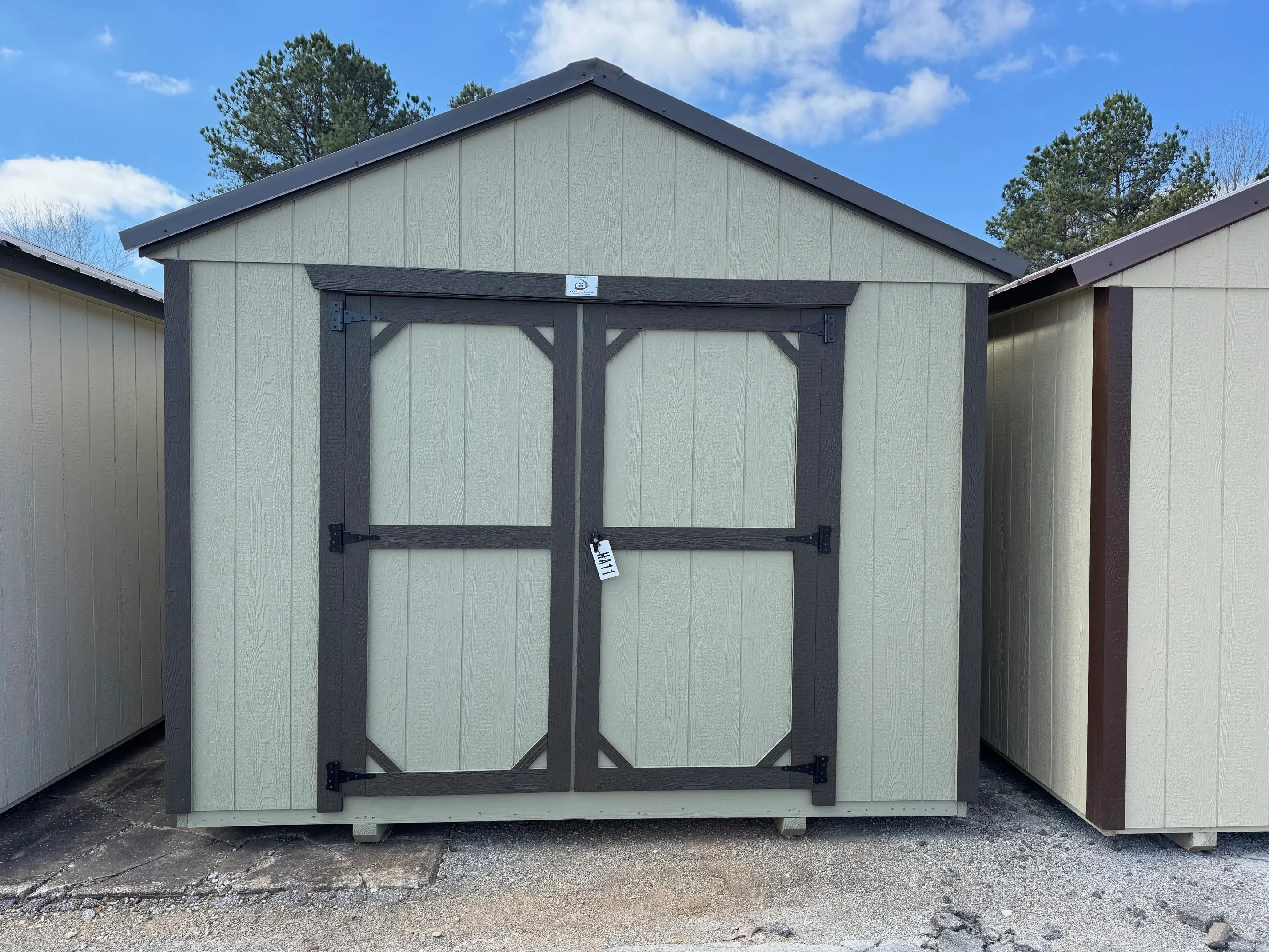 Outside of classic wood 10x12 utility shed with double doors wild grasses colored siding burnished slate roof.