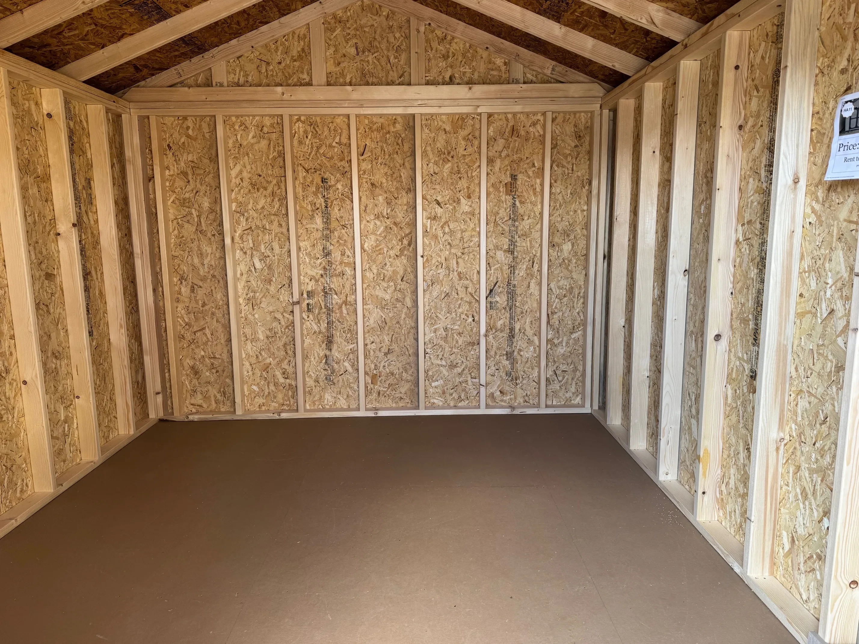 Inside of classic wood 10x12 utility shed with double doors wild grasses colored siding burnished slate roof.