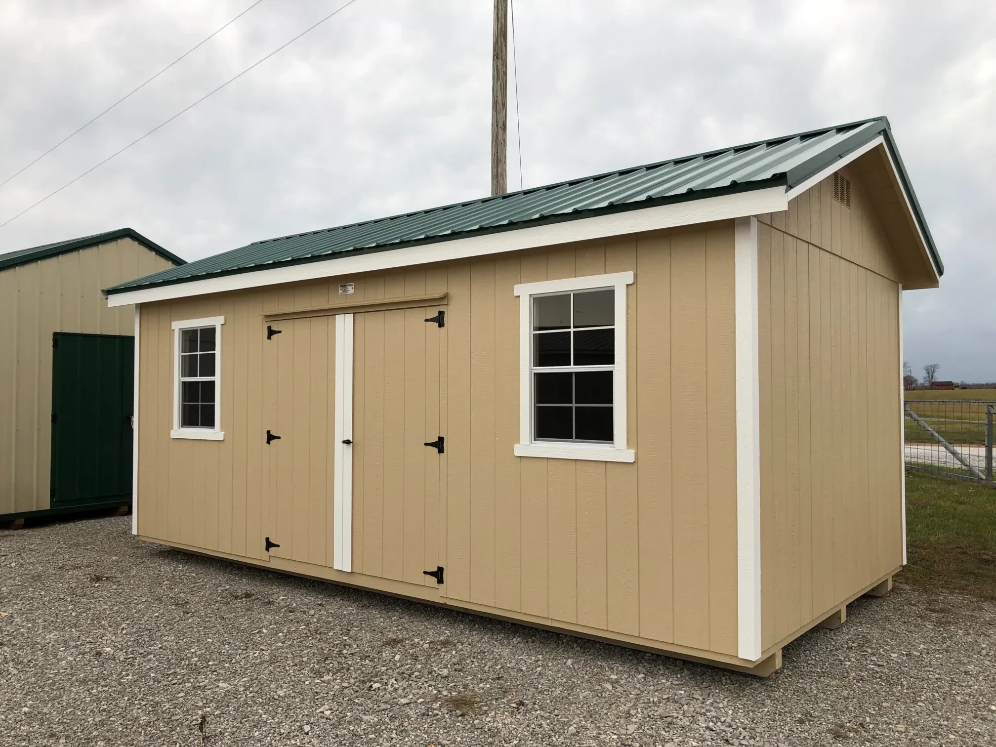 The front of a wood shed painted yellow with double doors and two windows