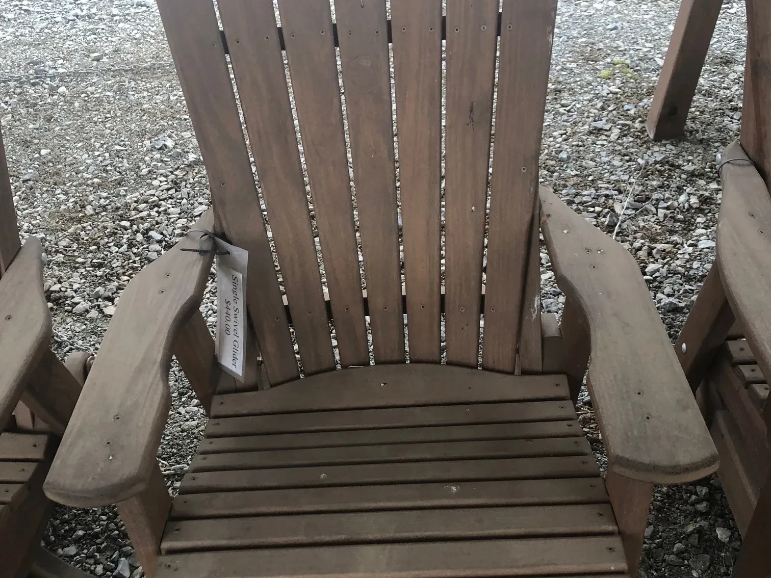 a wood chair sitting in the gravel. It can swivel and glide. It is stained and sealed