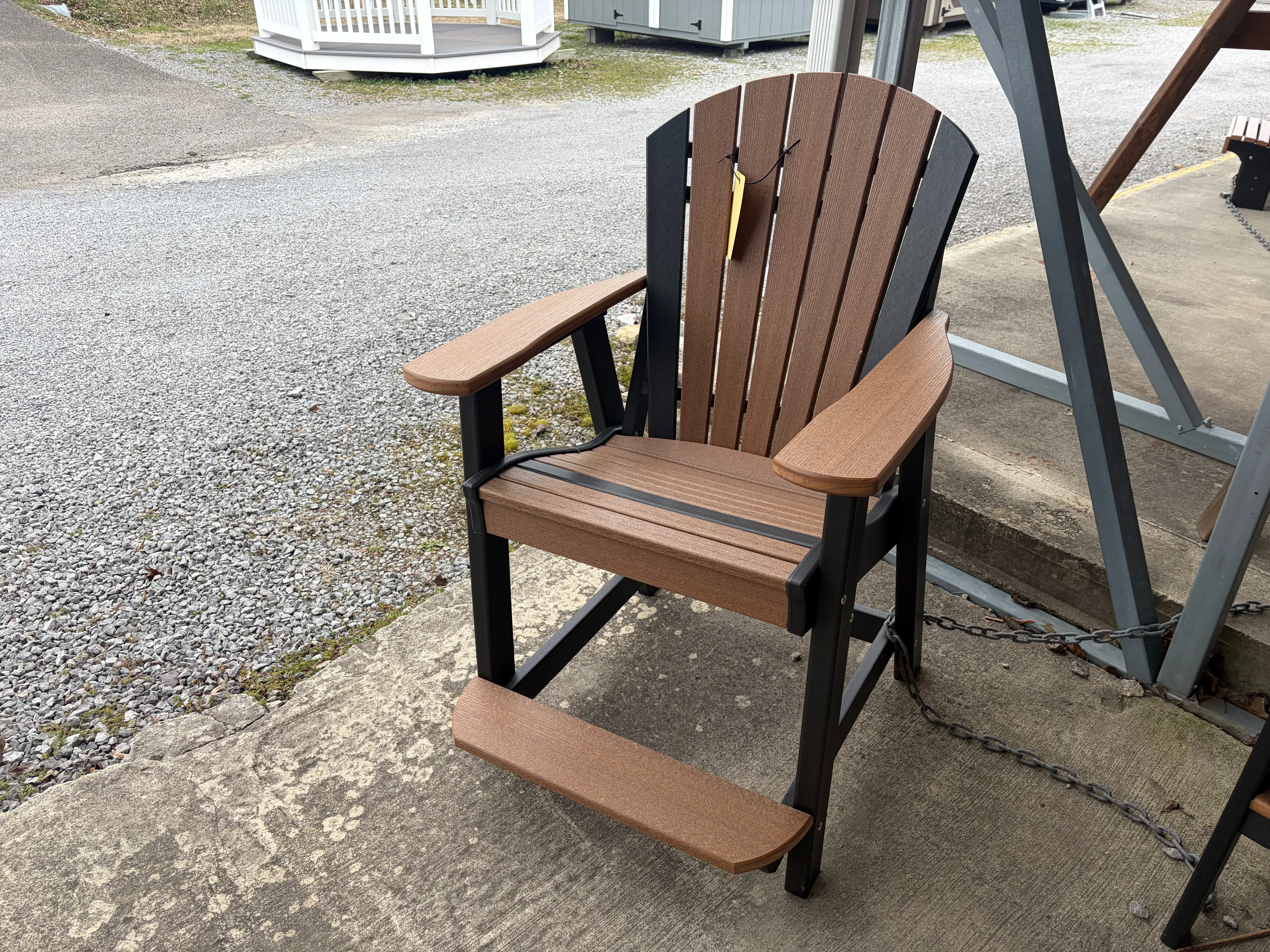 a brown chair with black accents sitting on concrete. It has a yellow price tag and is chained up to other furniture nearby