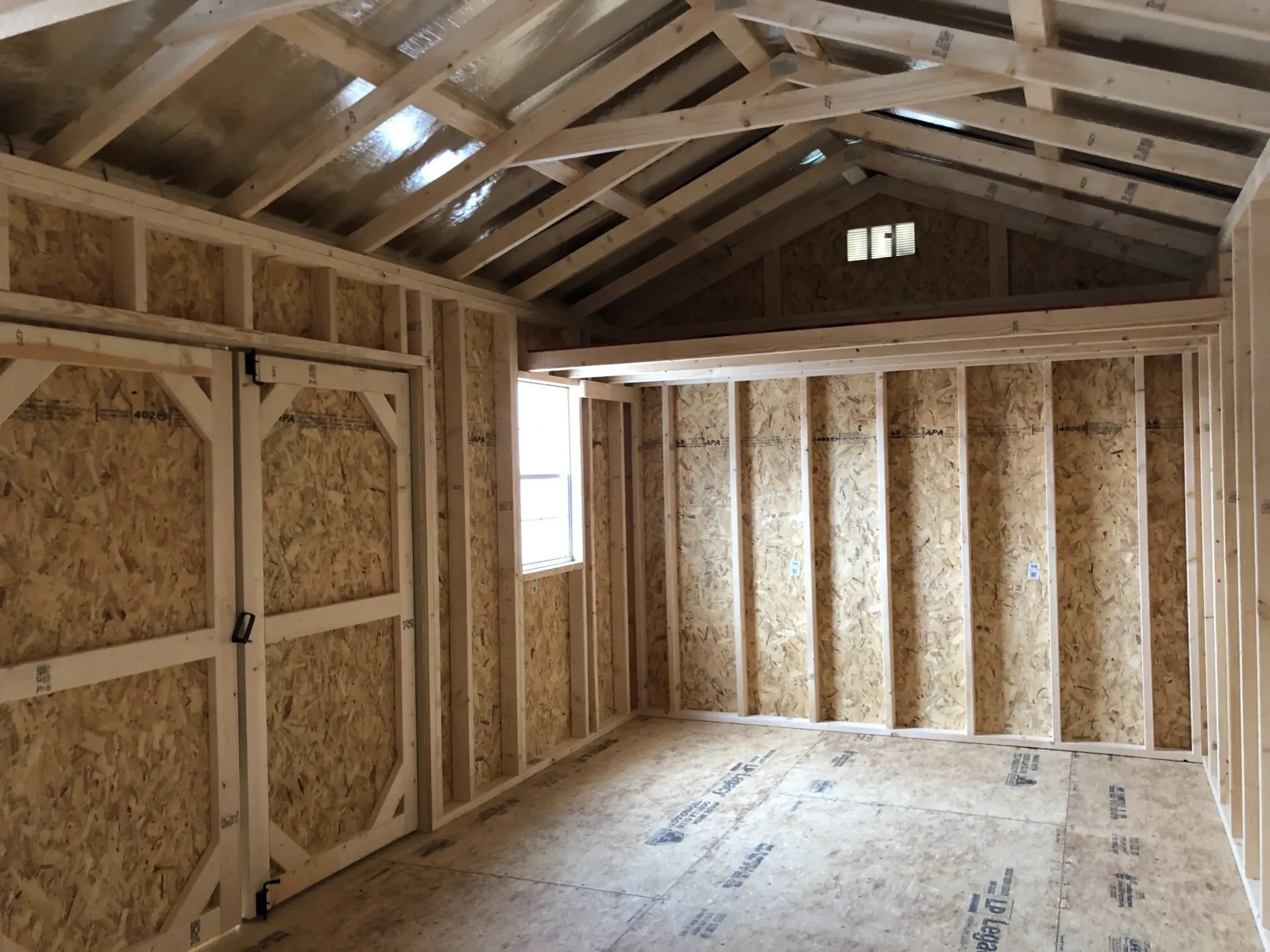 The inside of a wood shed showing a window and a loft