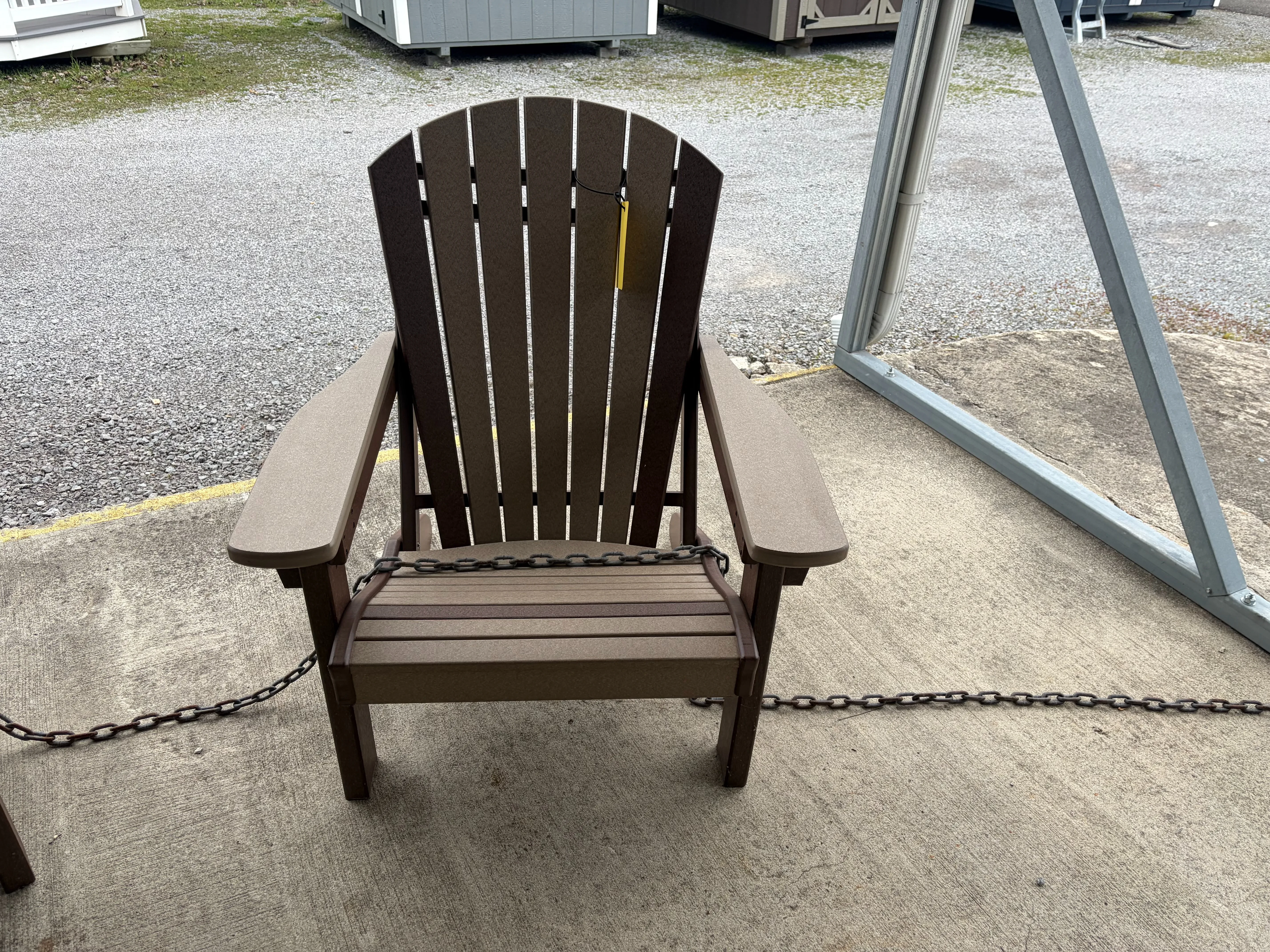 a light brown chair with dark brown accents sitting on concrete. It has a yellow price tag on it and is chained up