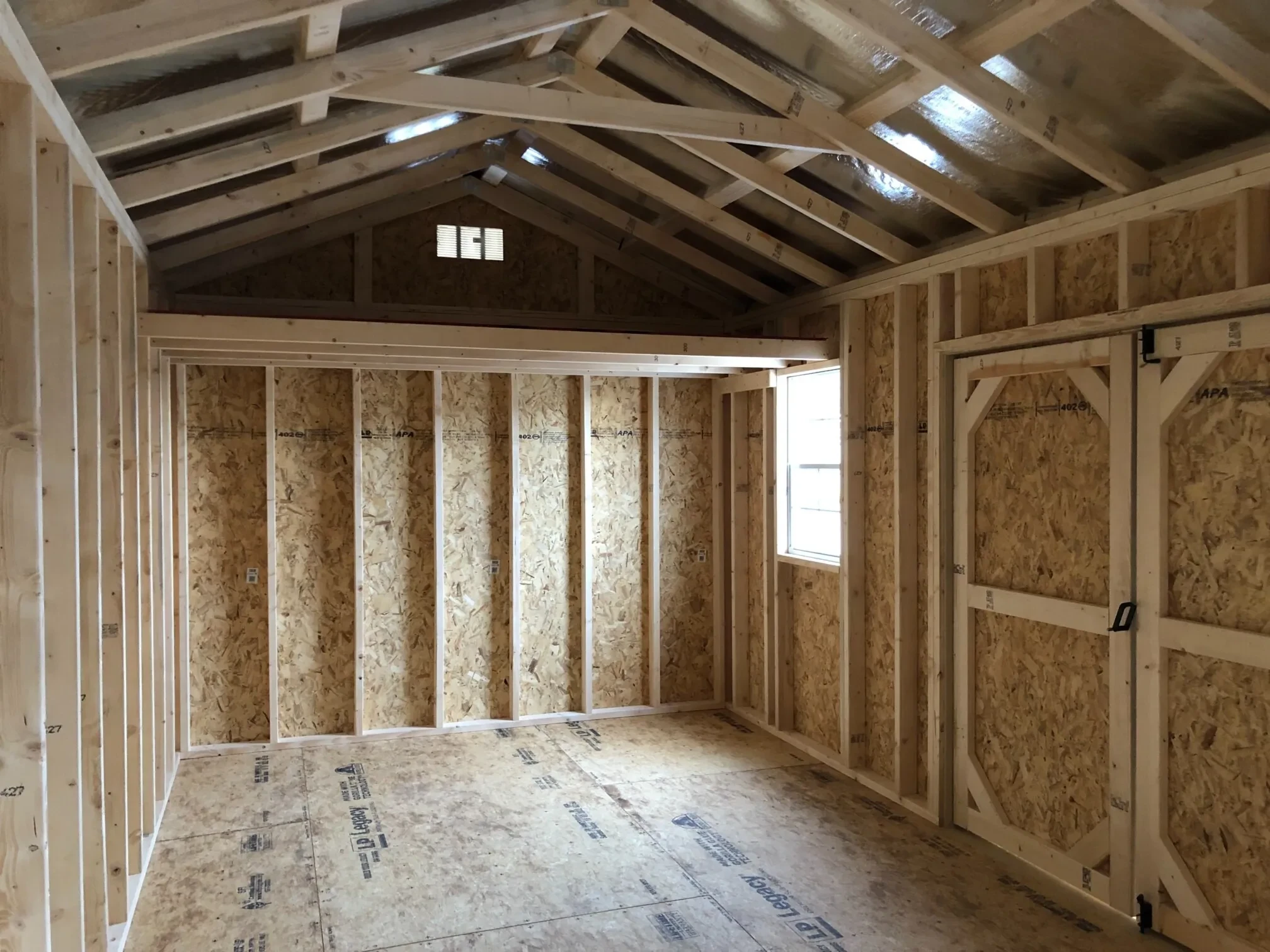 the inside of a wood shed showing a loft and a window