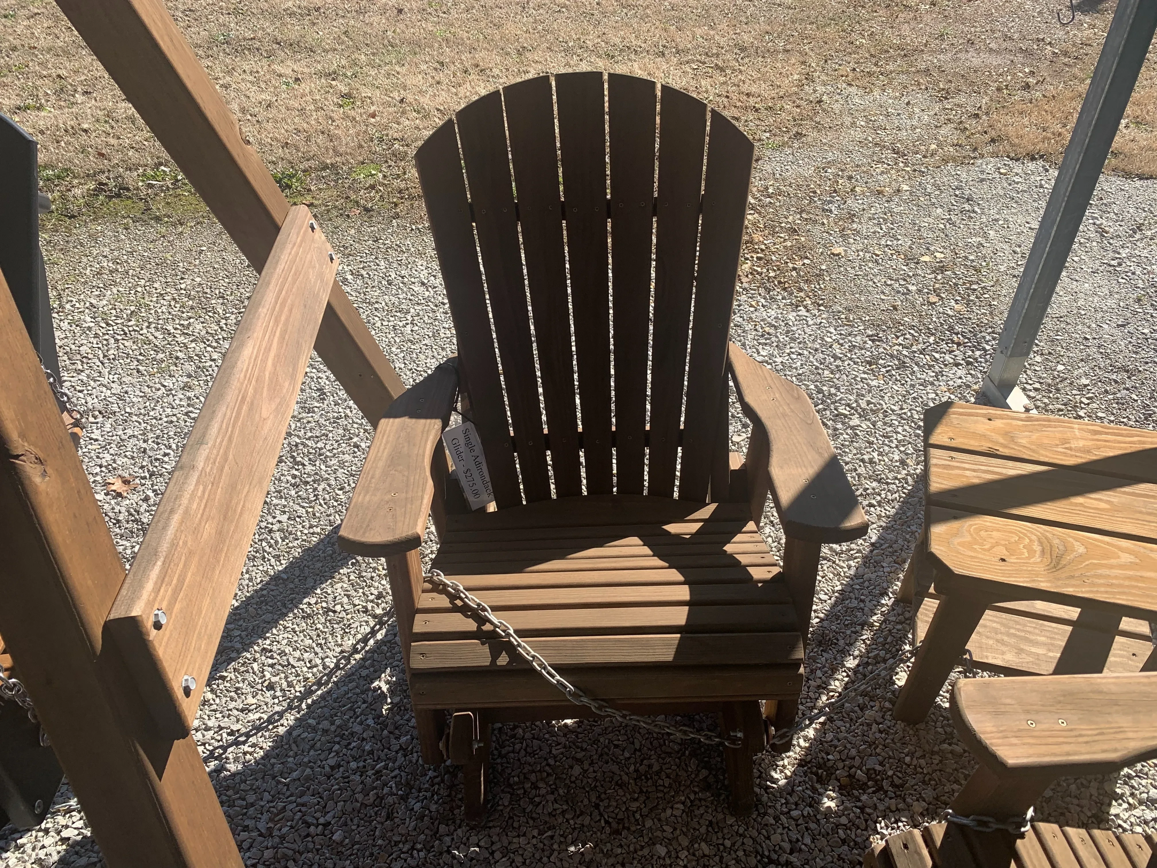 a chair sitting in the gravel. It is stained and sealed. It can glide back and forth and is chained up to other furniture