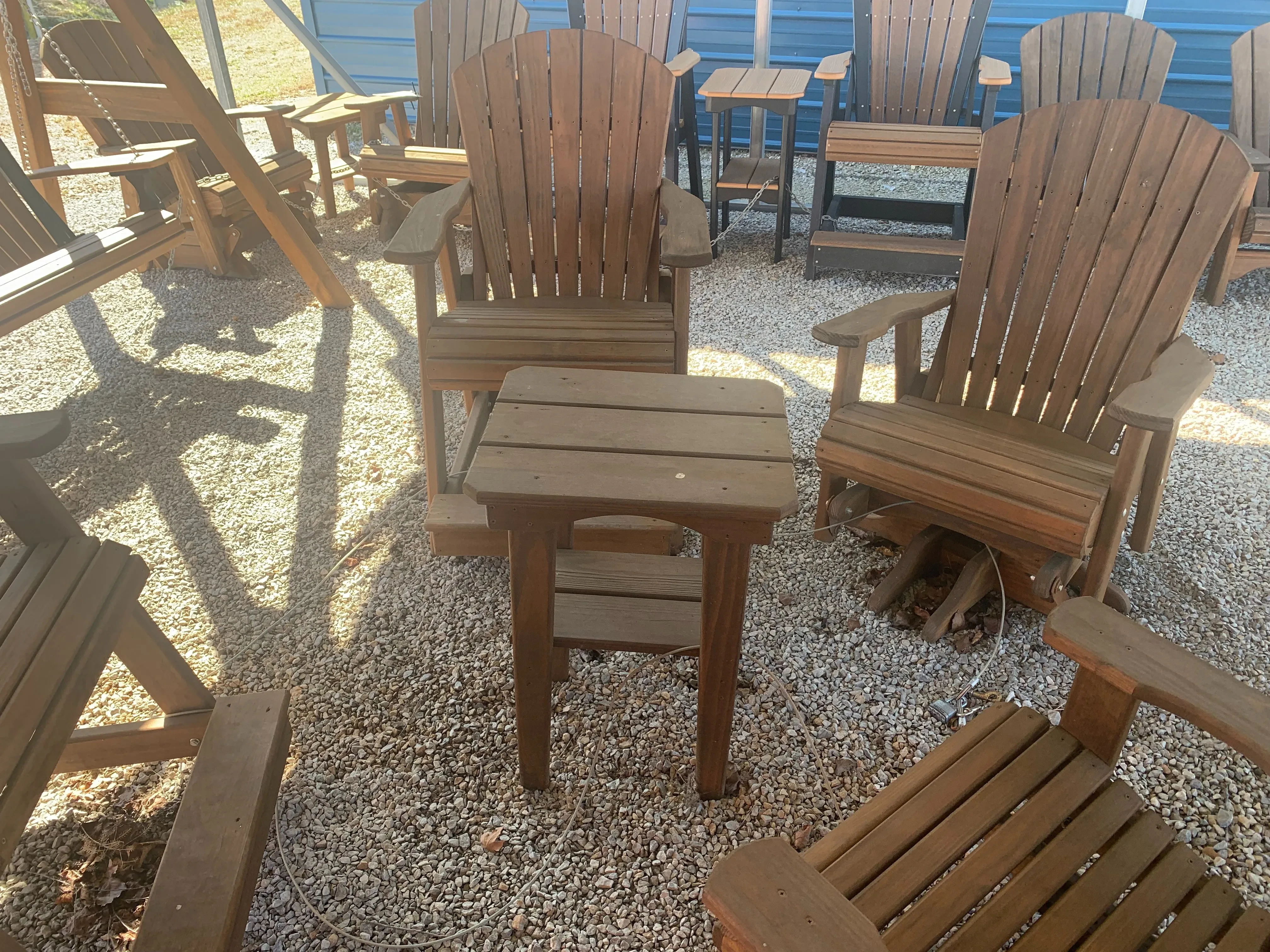 a table sitting in gravel. It is surrounded by chairs and other furniture. It is stained and sealed