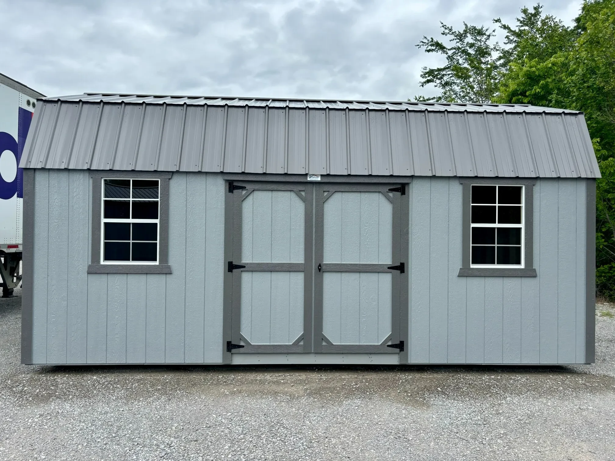 The side of a lofted garage showing windows and double doors