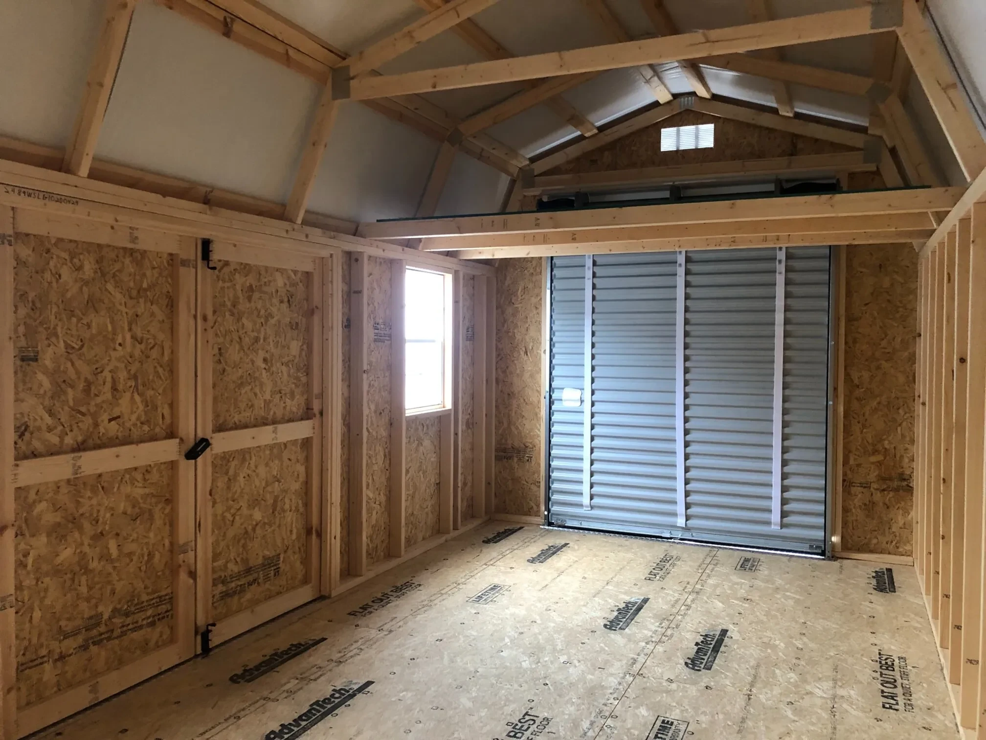 The inside of a lofted garage showing the double doors closed as well as the garage door