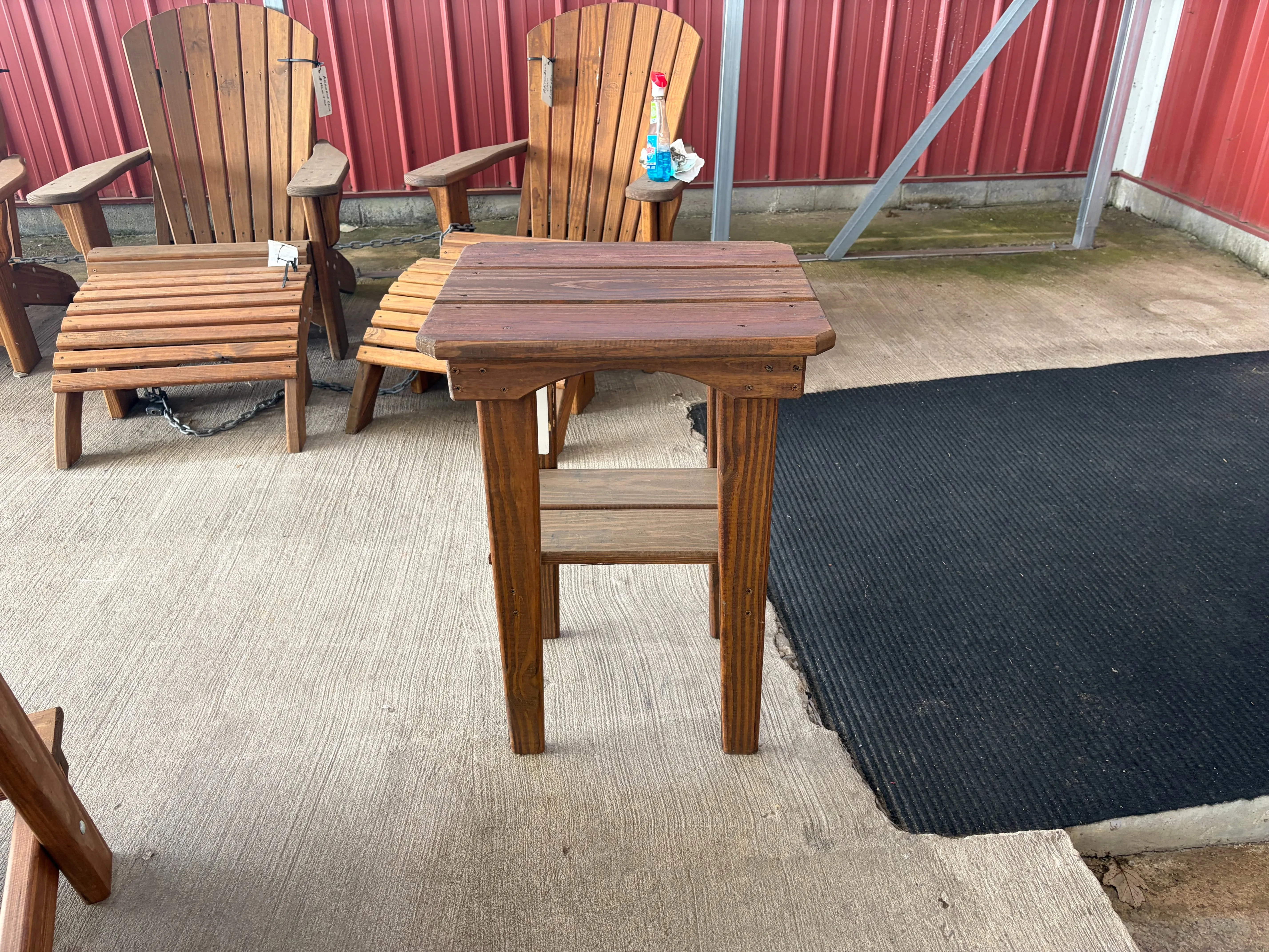 the side view of a wood stained and sealed table. There is other furniture in the background. It is next to a black carpet