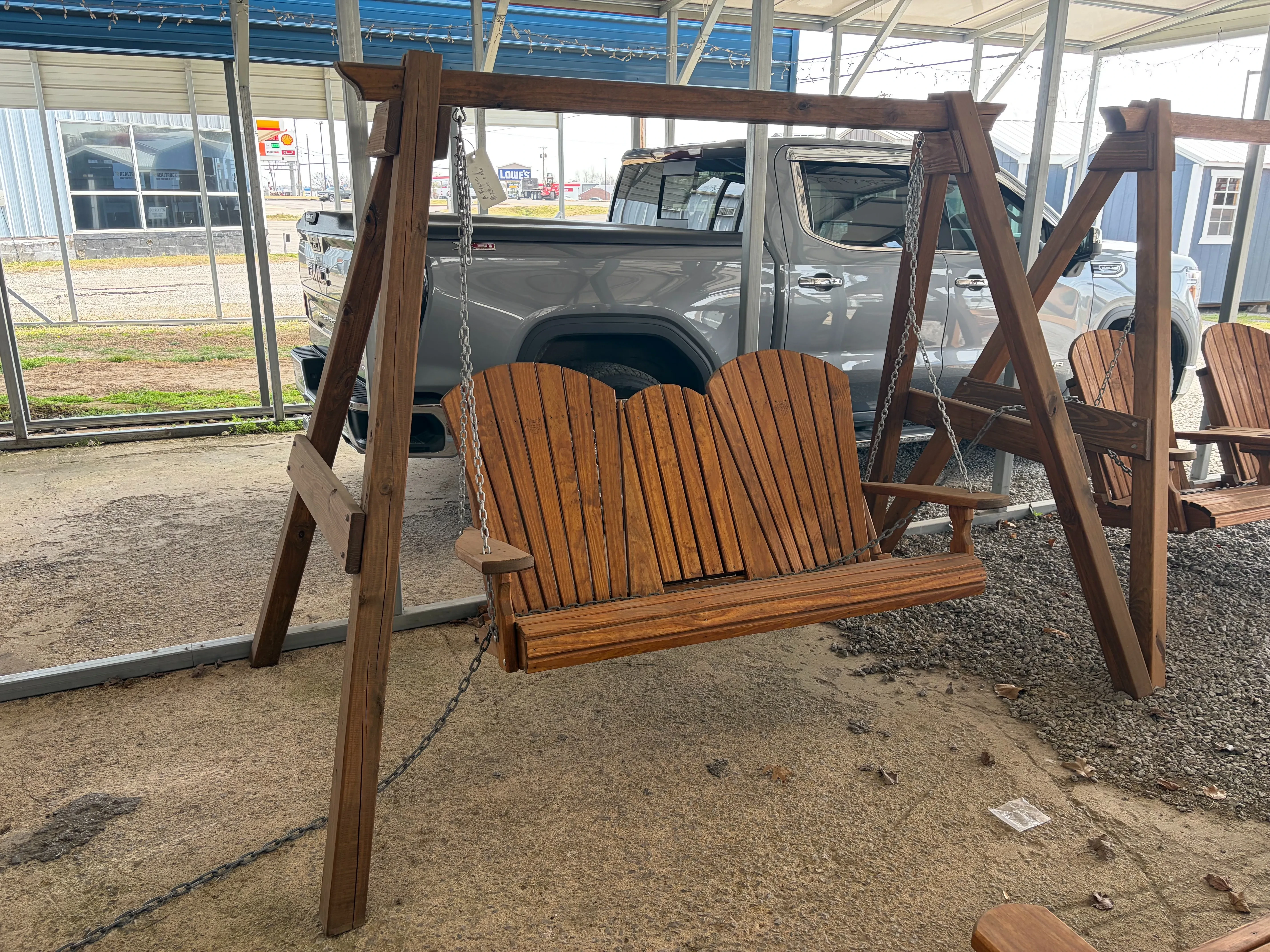 a wooden a-frame structure holding up a wood bench swing with chains. It is stained and sealed.