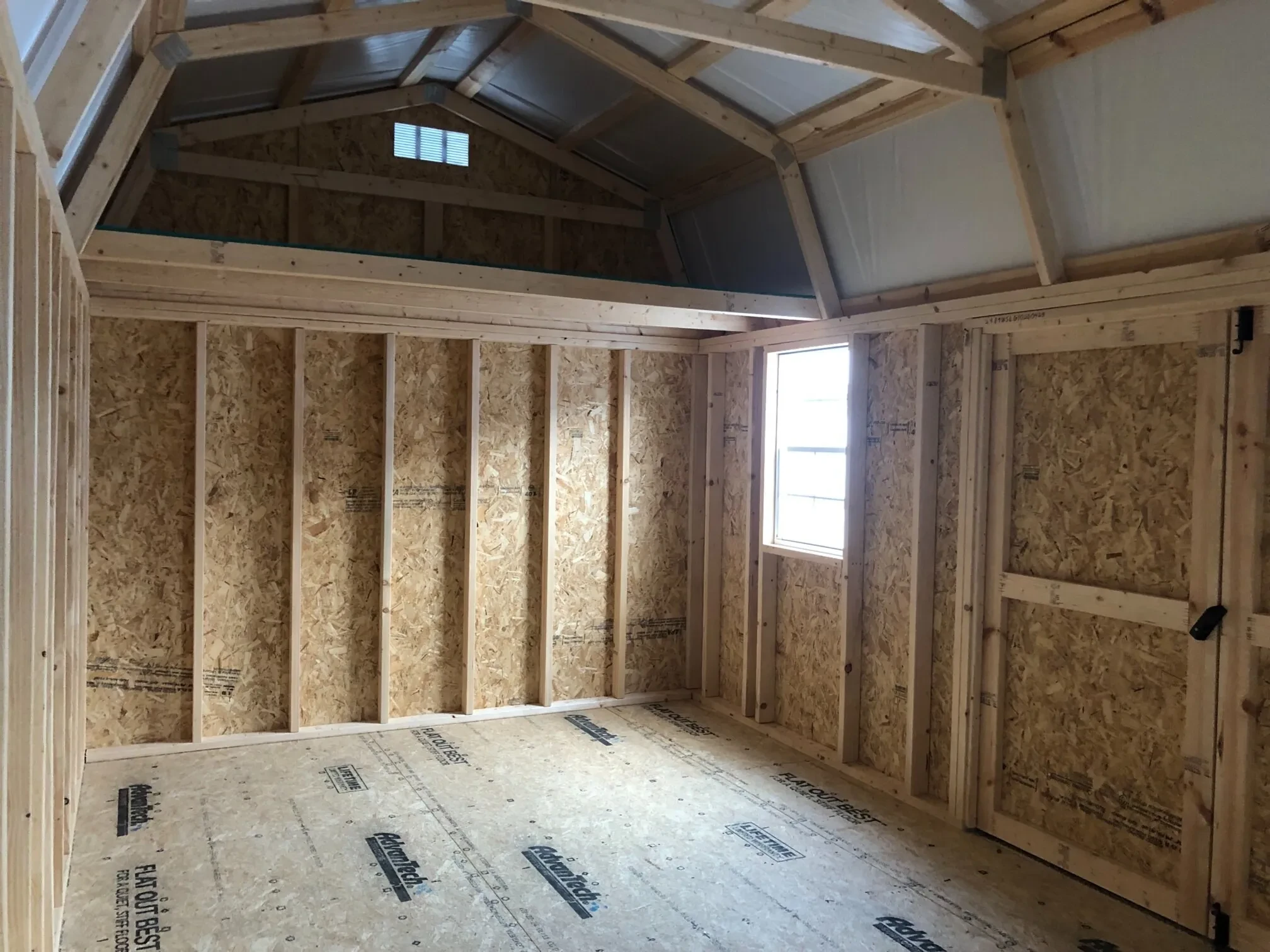 The inside of a lofted garage showing a loft and a window