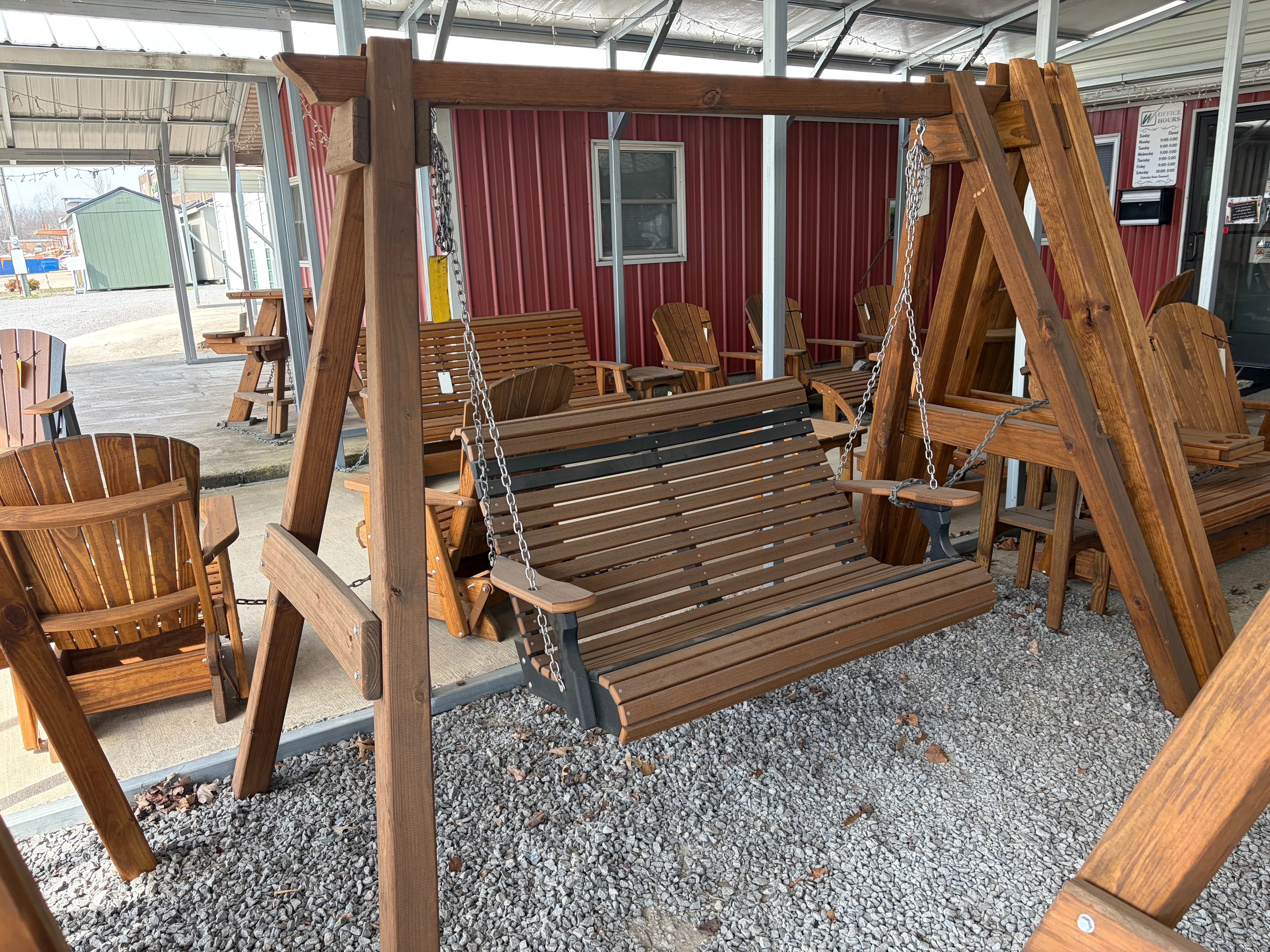 a wood a-frame structure holding up a polywood bench swing by chains that is brown with black accents.