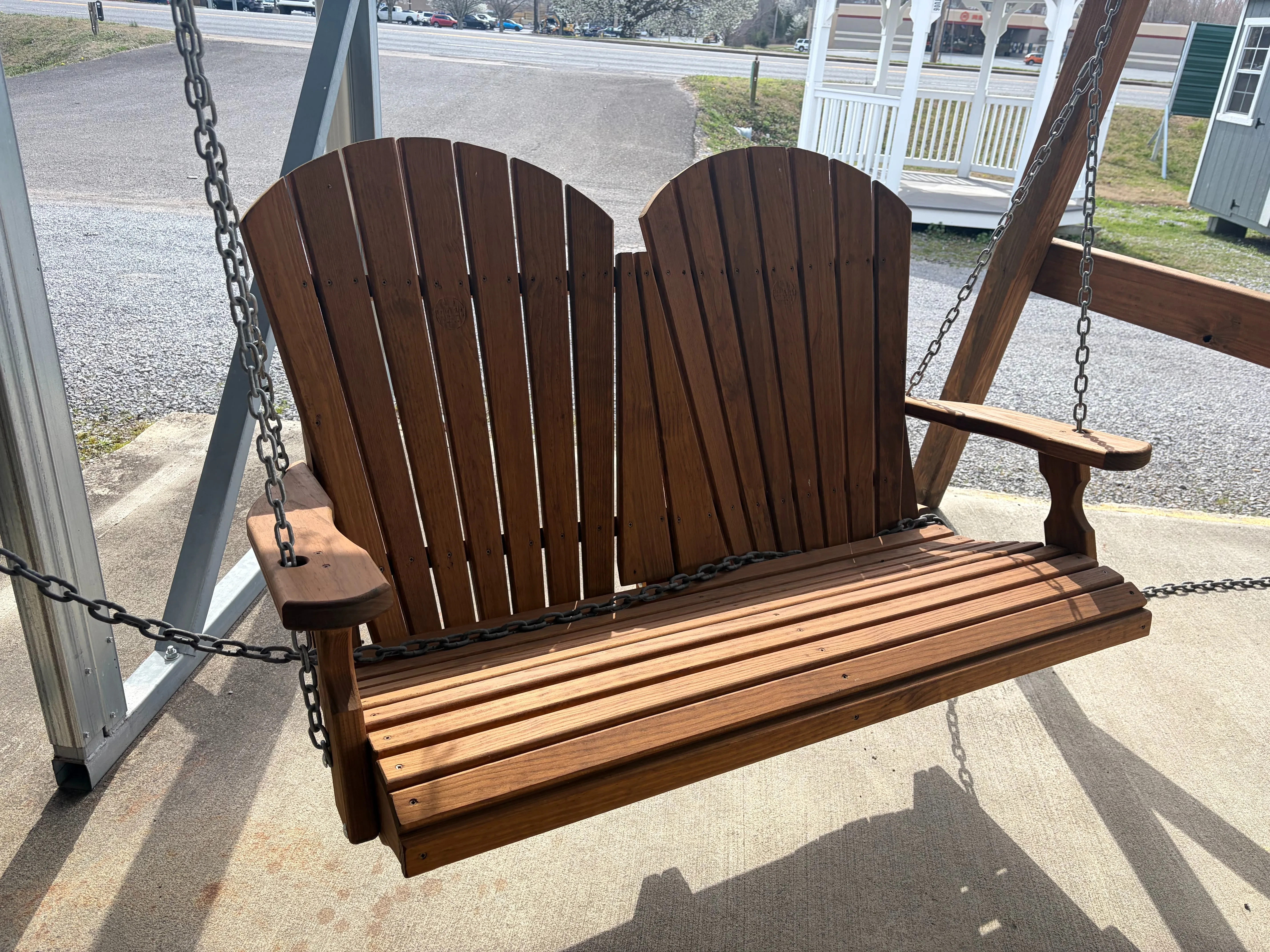 a bench swing hovering above concrete. It is being held up by chains. It is stained and sealed to last