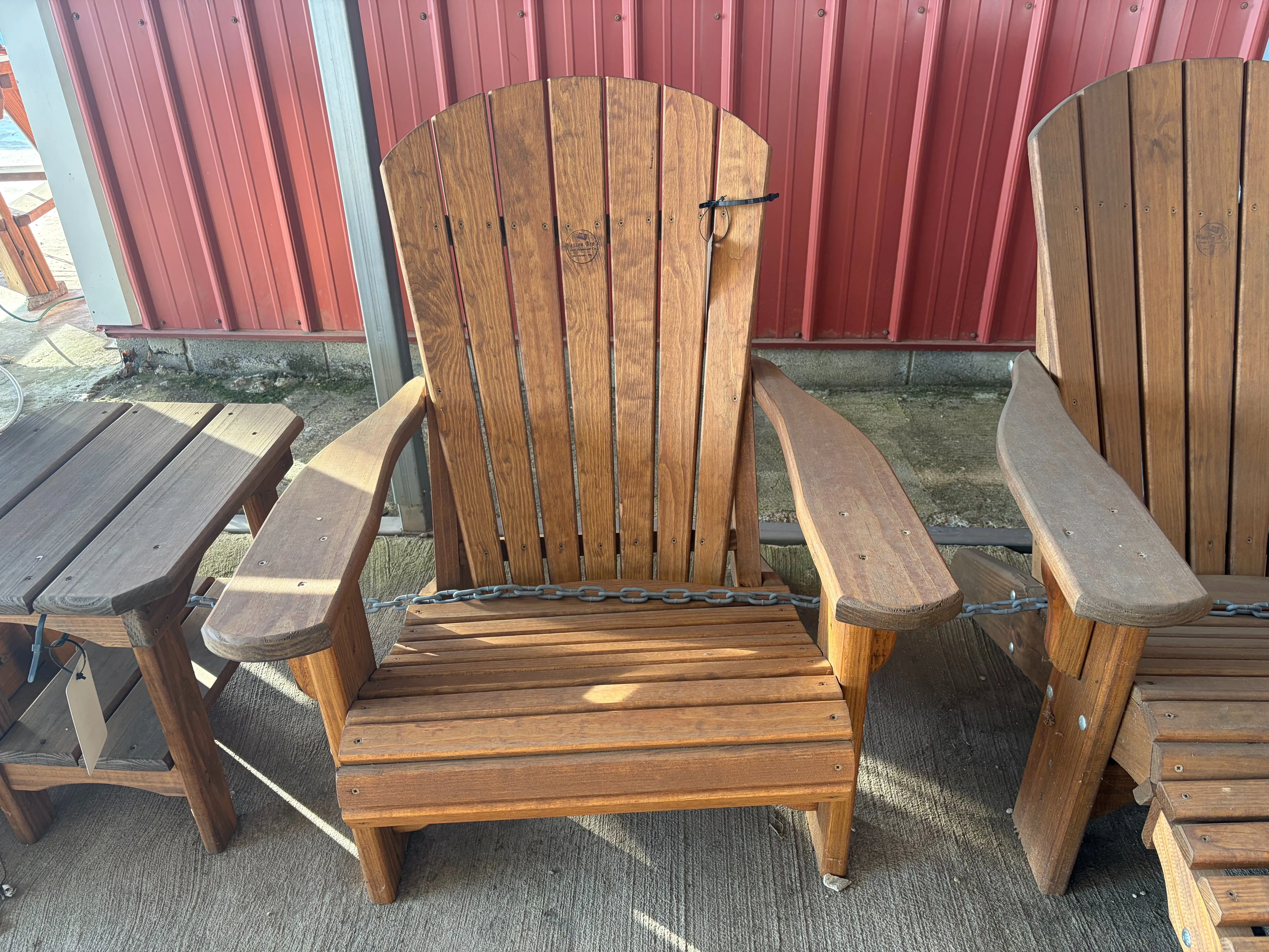 a wood chair chained up to other furniture. It is stained and sealed. It has furniture next to it