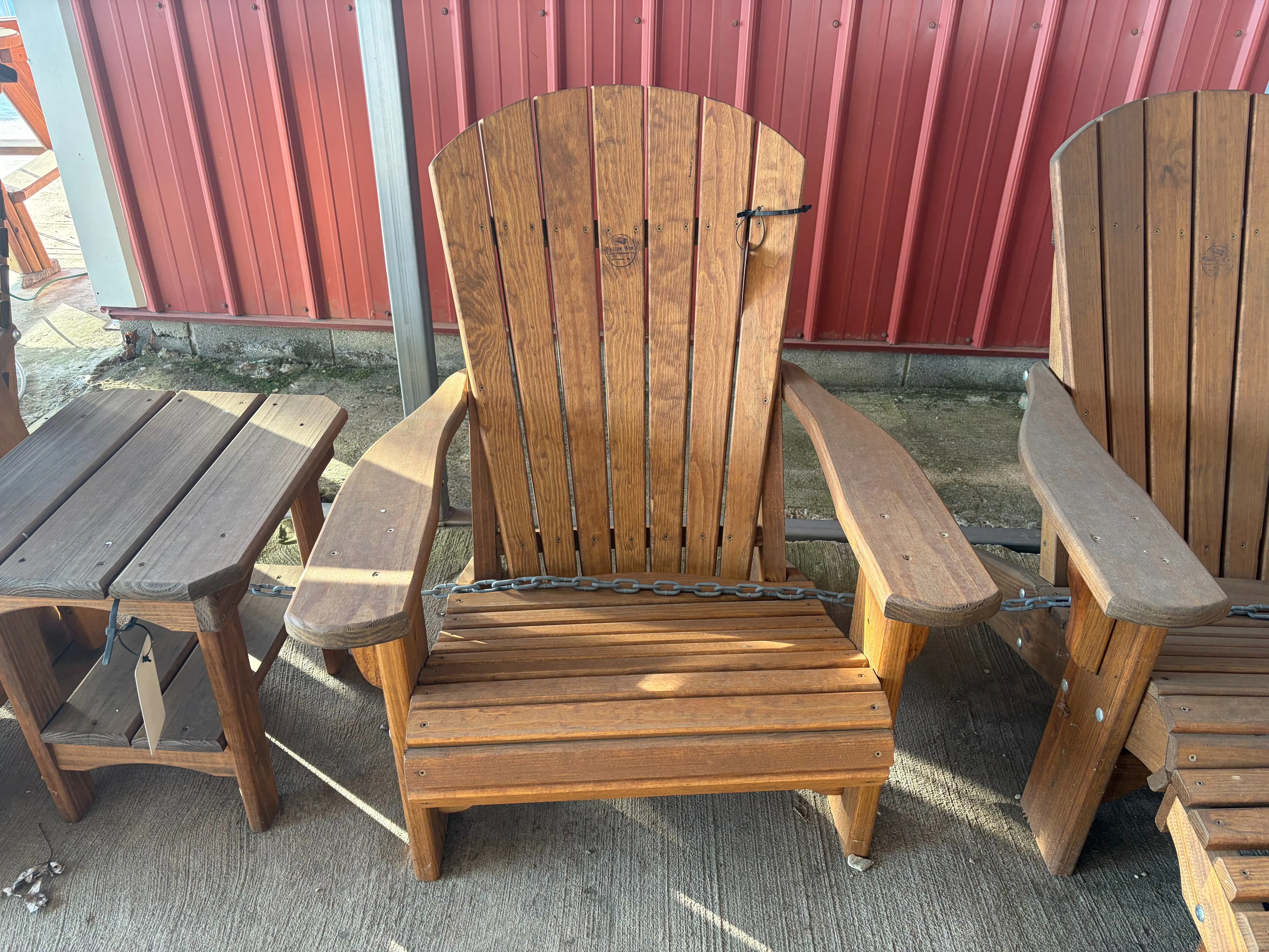 a wood chair sitting next to other furniture. It is stained and sealed. It has armrests.