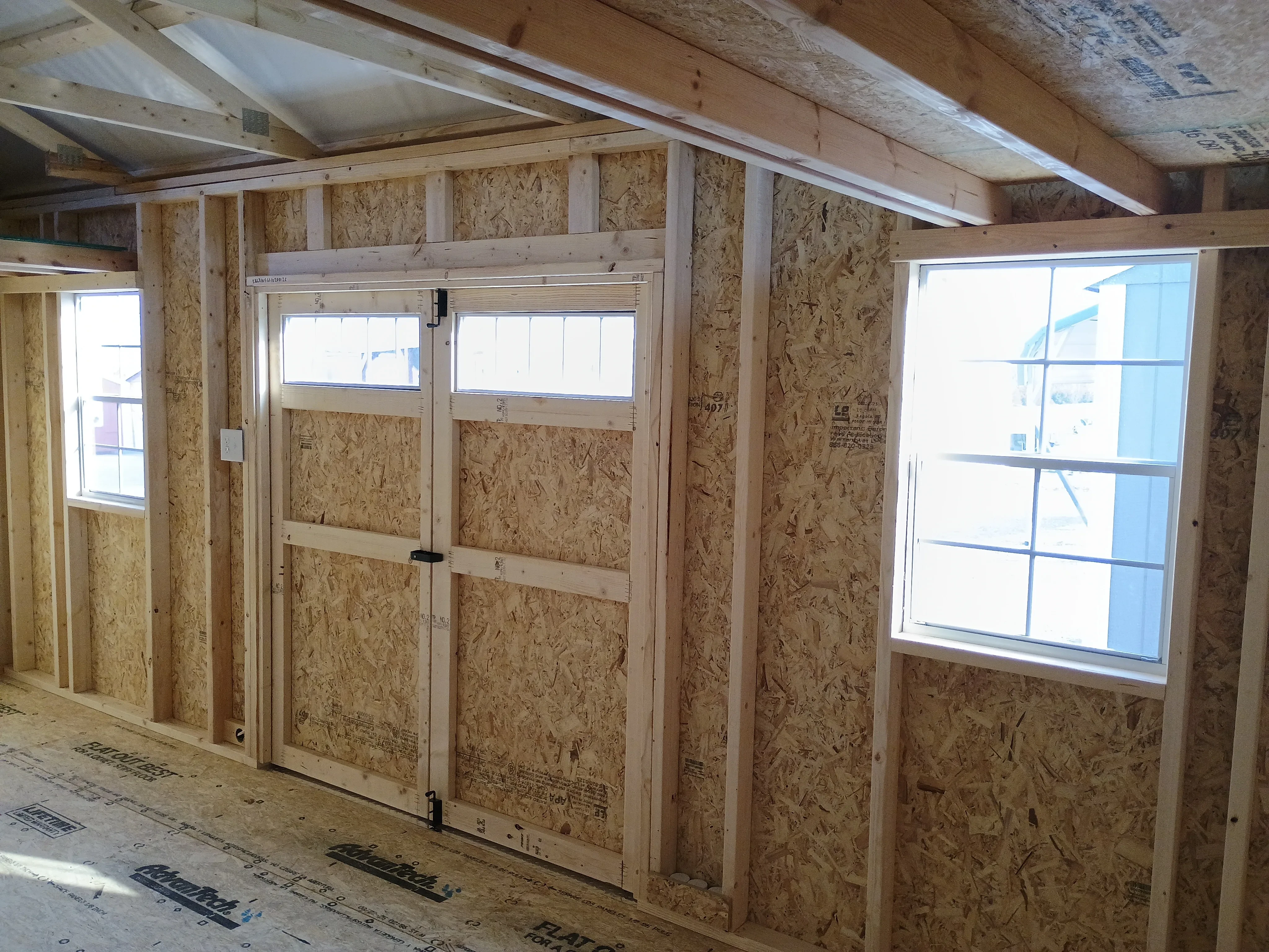 10x20 wood garden shed interior, showing 2 windows on the side, transom windows on doors, and electric switch and outlet