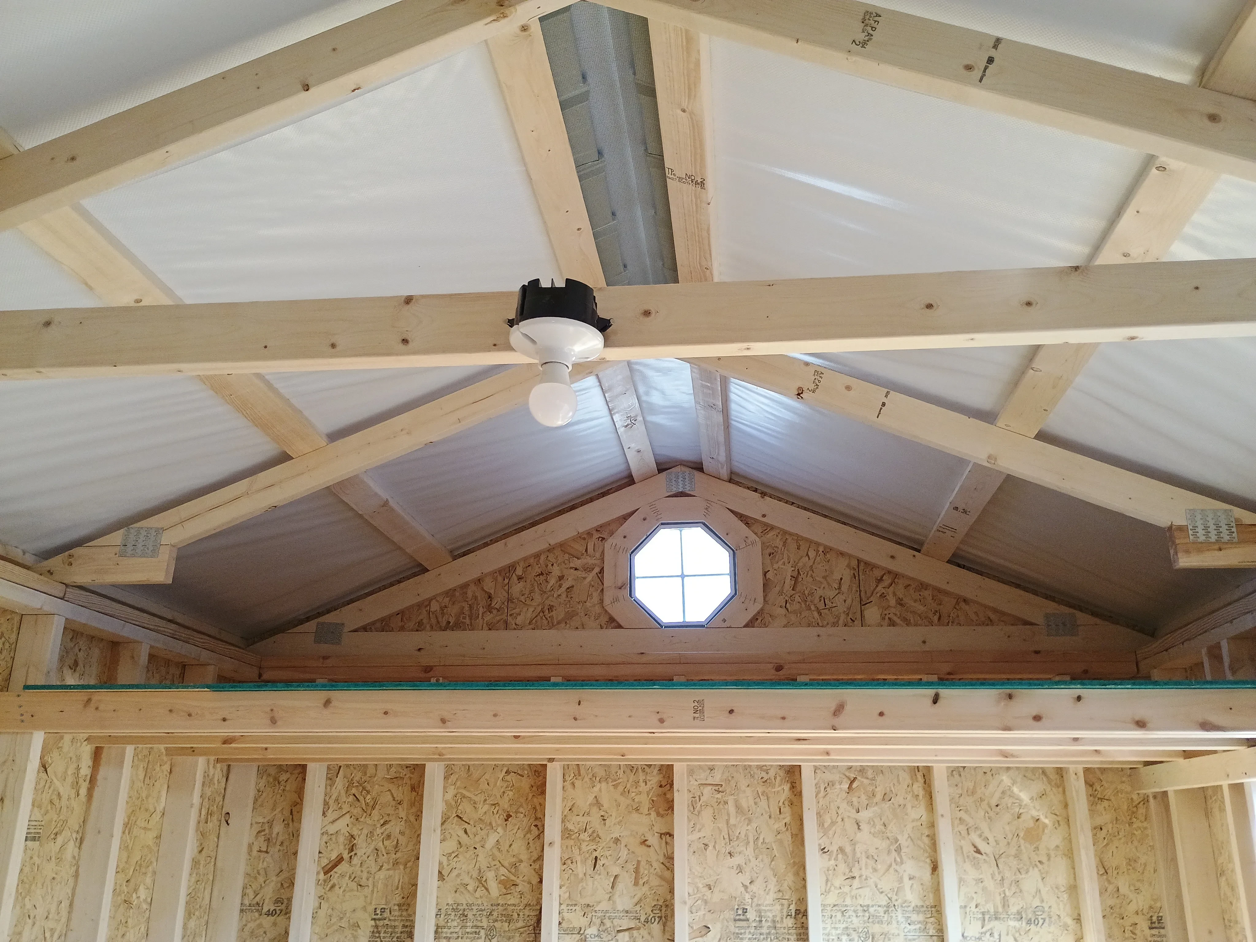 10x20 wood garden shed interior, showing 1 loft (of two), 1 octagon window (of two), and light bulb of electric package