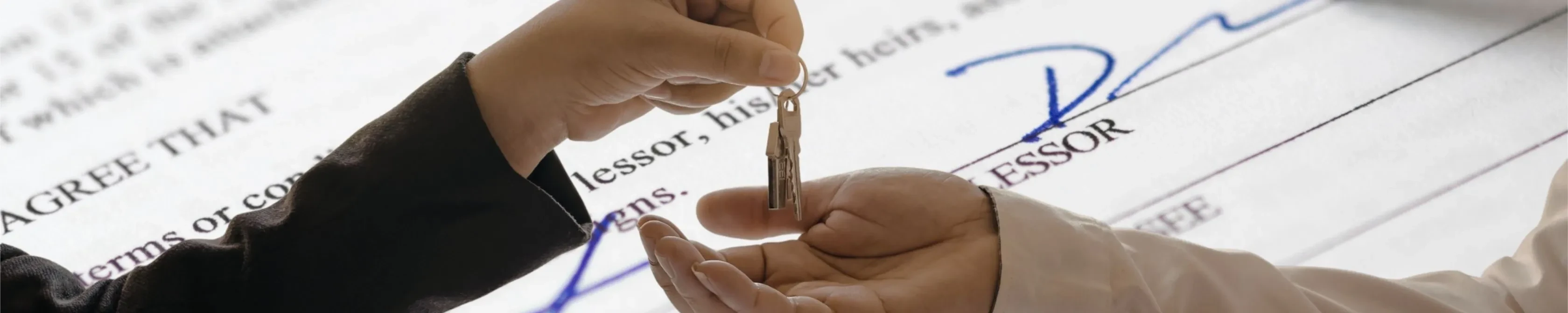 rental agreement in the background with a key being placed into an open hand.