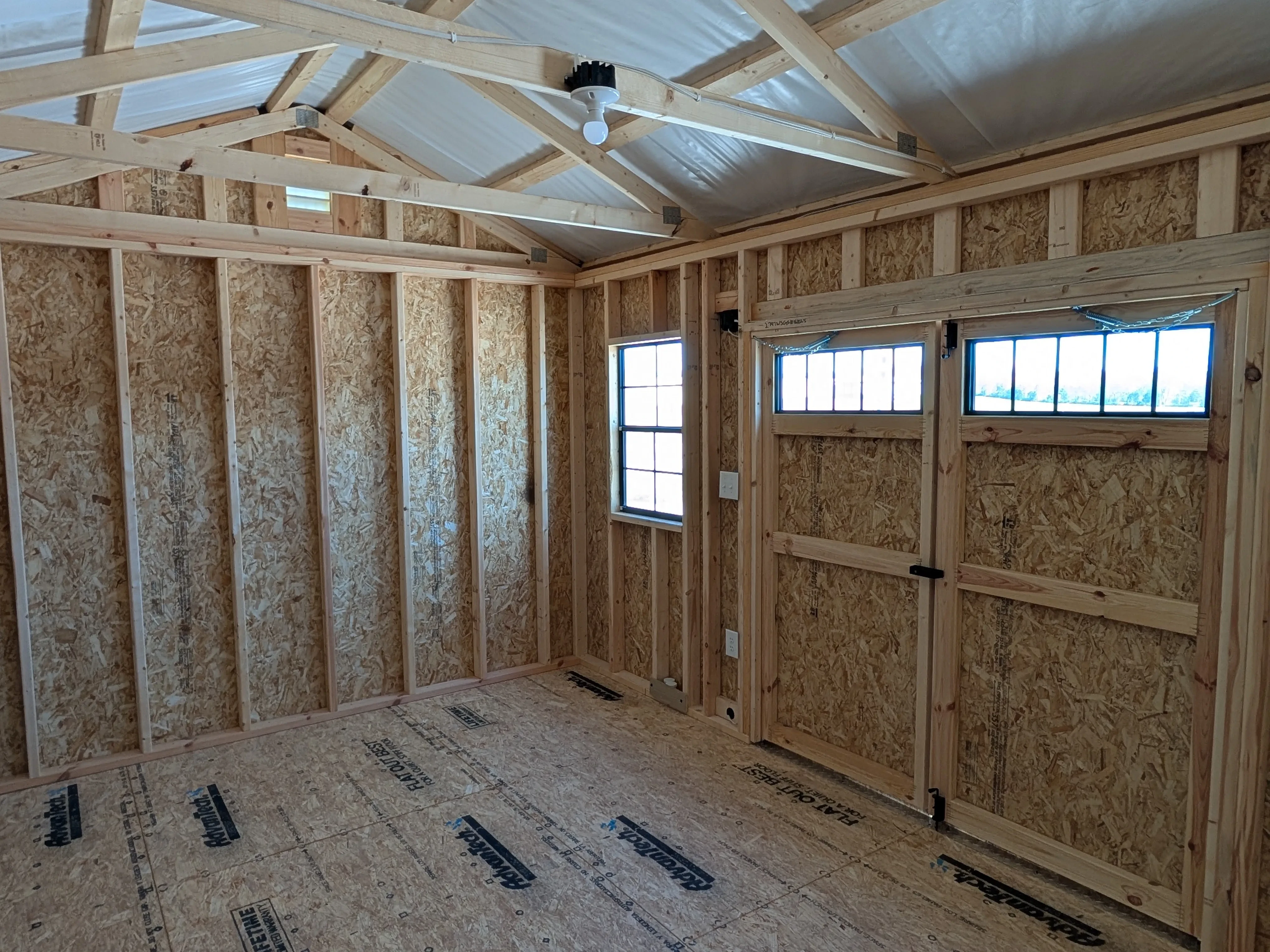 inside a wood garden shed looking at the right and front walls. Light is coming through the window and the transom windows