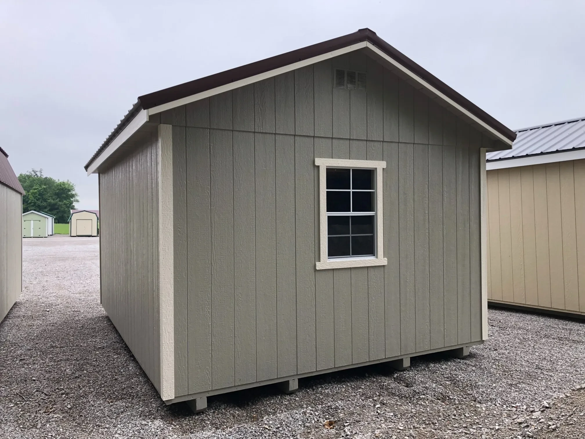 The back of a gray wood shed showing a window in the middle of the back wall