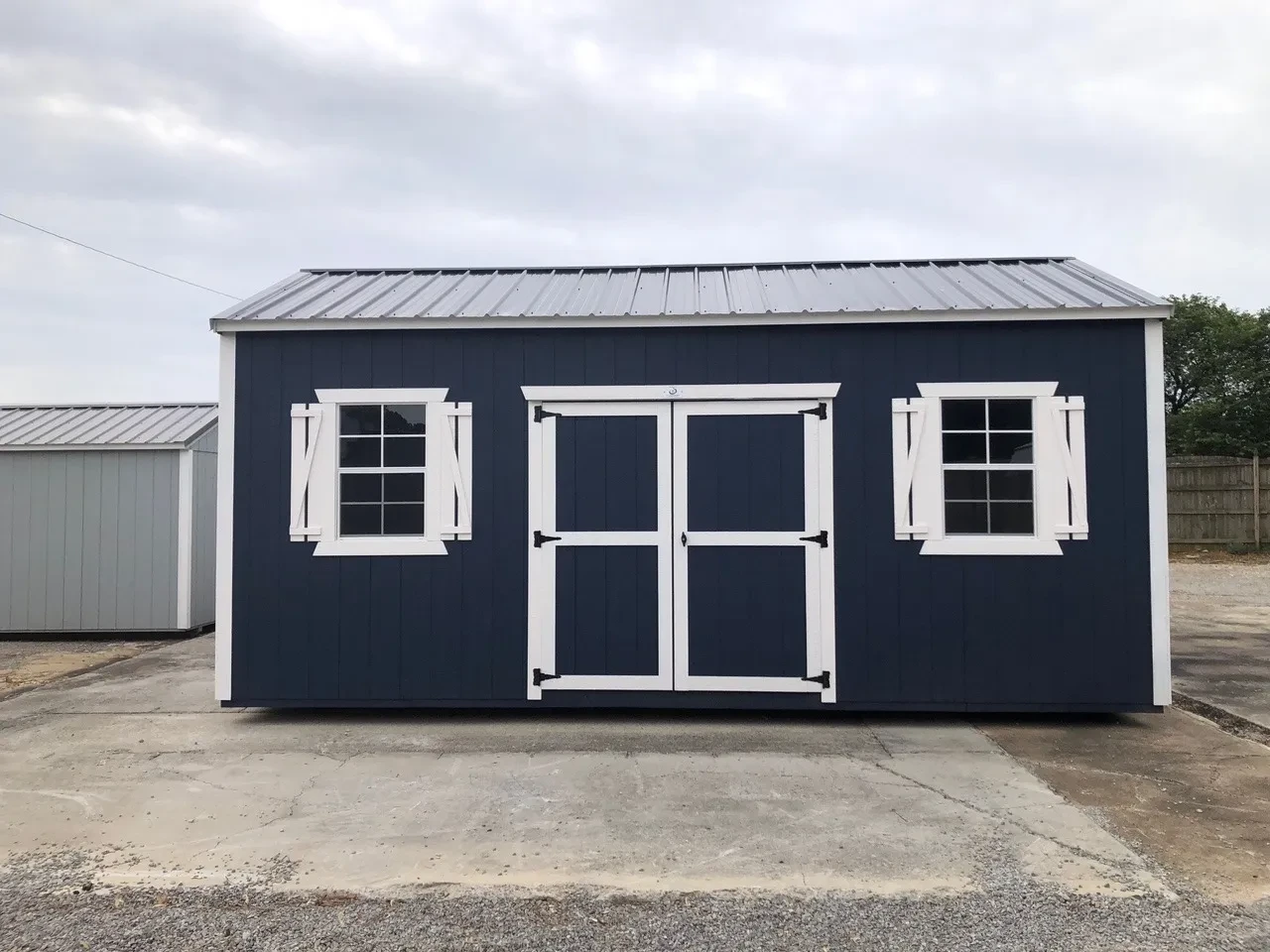 exterior of blue shed showing double doors and windows with shutters