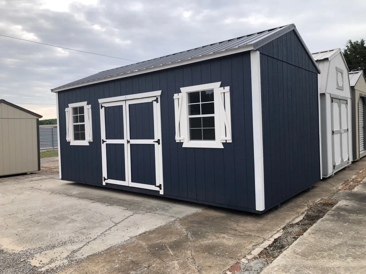 exterior of blue shed showing double doors and windows with shutters