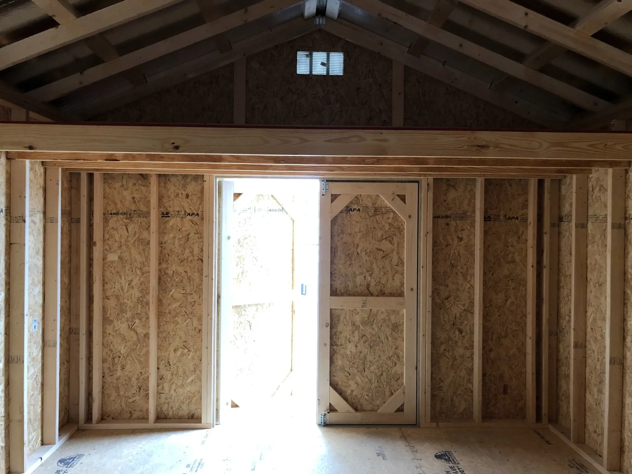 The inside of a wood shed showing a loft with double doors open underneath