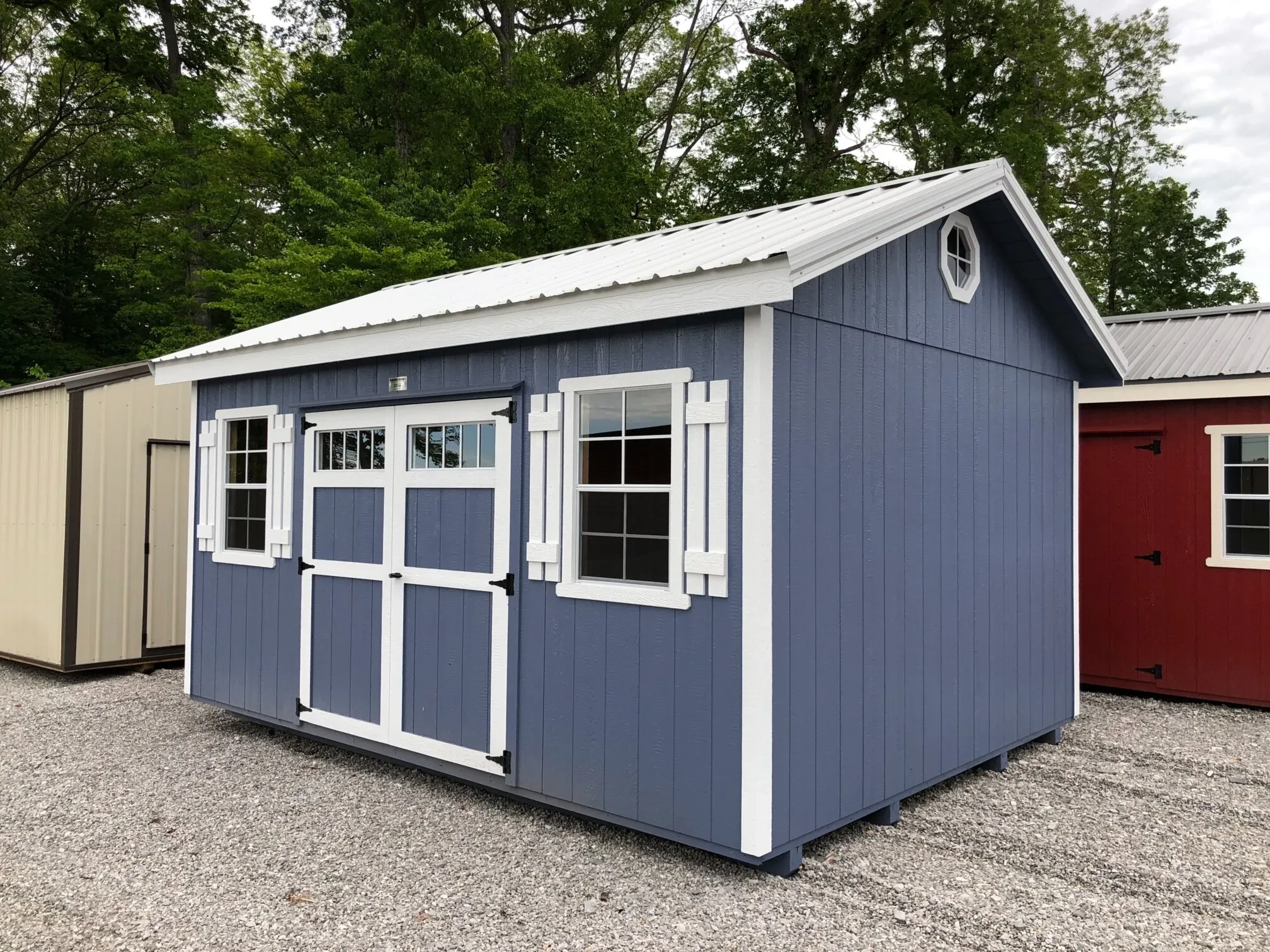 A blue shed with windows and shutters with a white roof