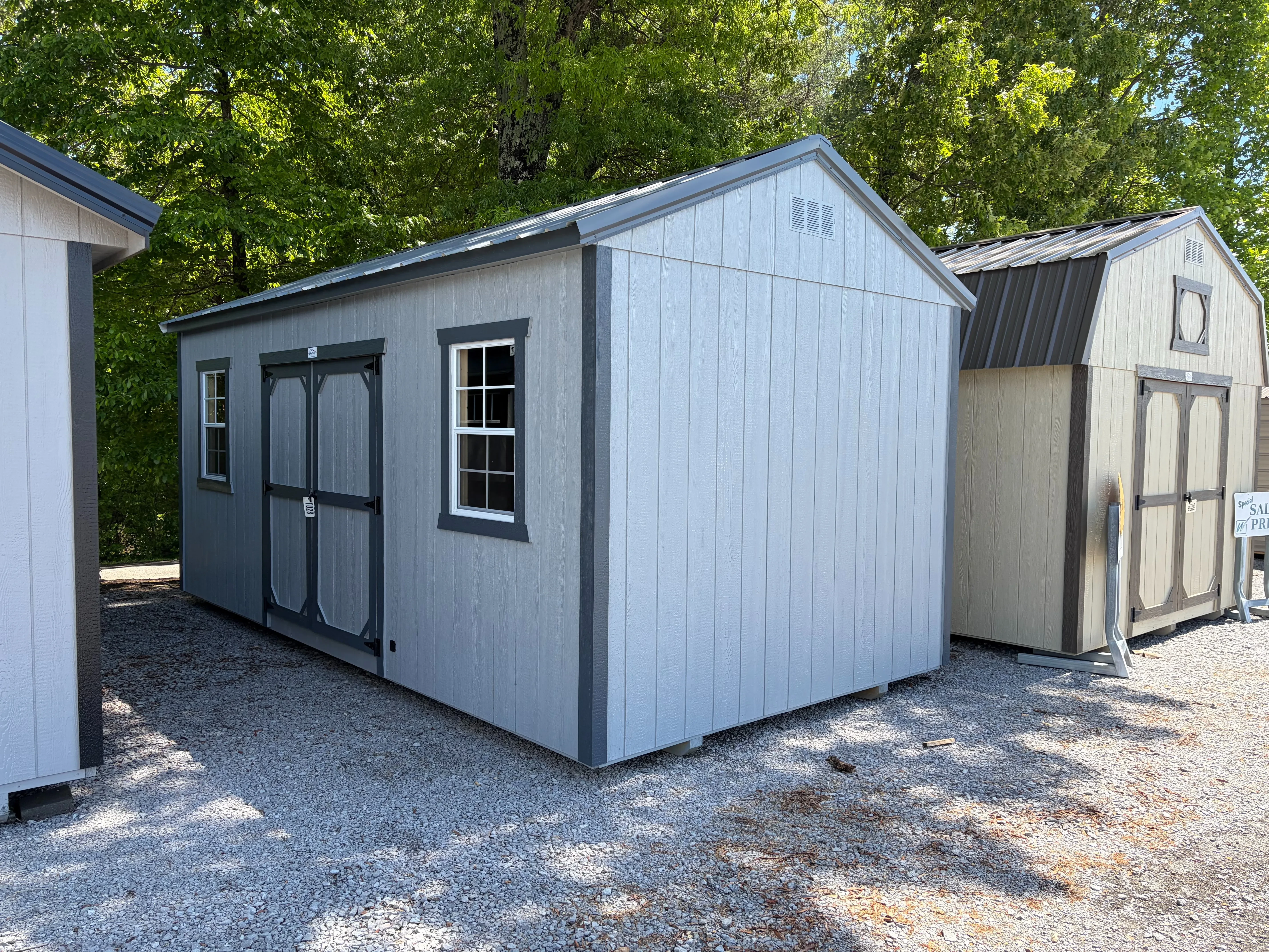 a light gray garden shed with slate gray trim and it has a window on each side of the double doors