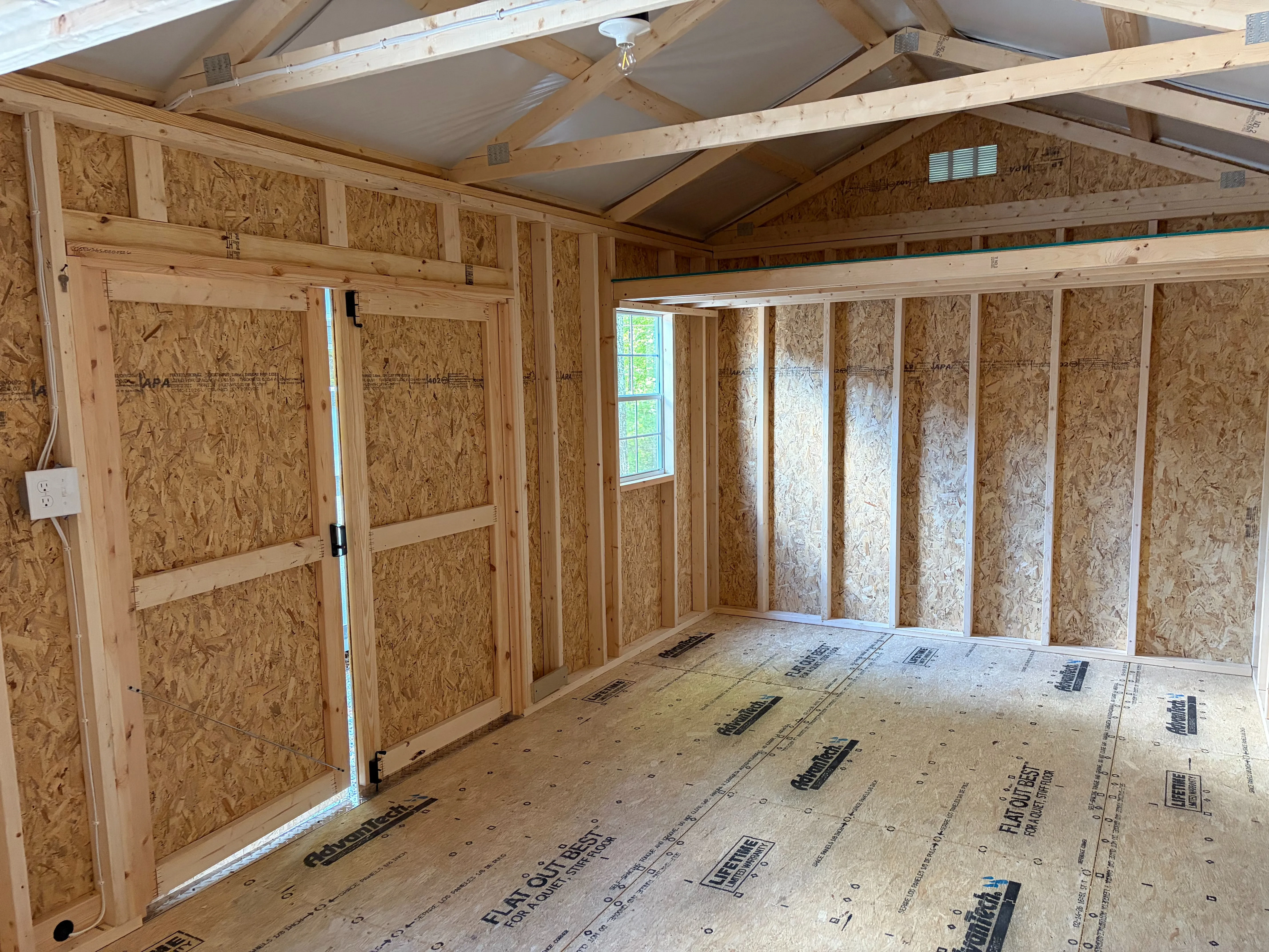the right interior of a wood garden shed which has a window on the front wall with electrical package and loft