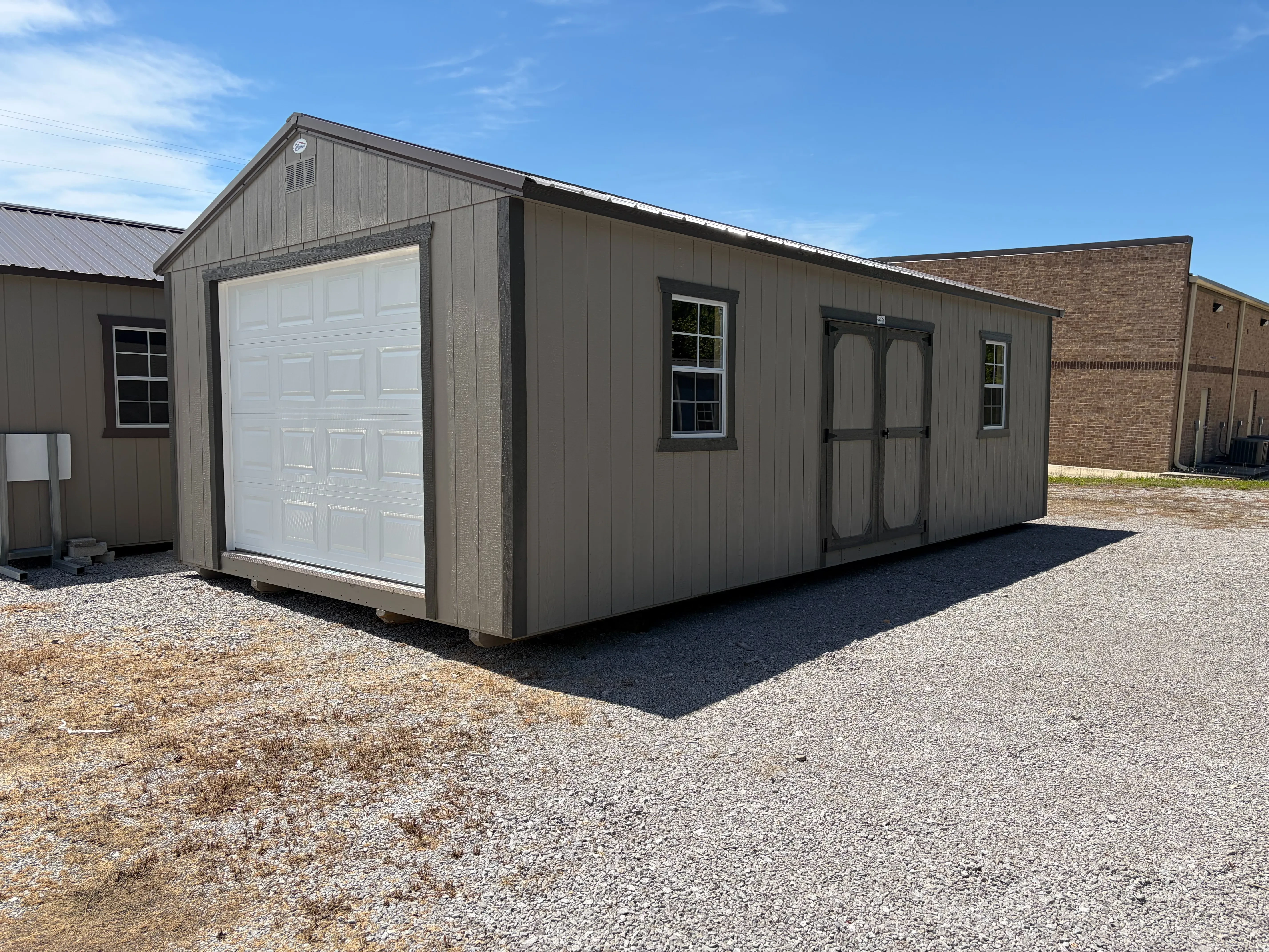 a wood garage shed with a overhead door in the front and double doors and windows on the right side