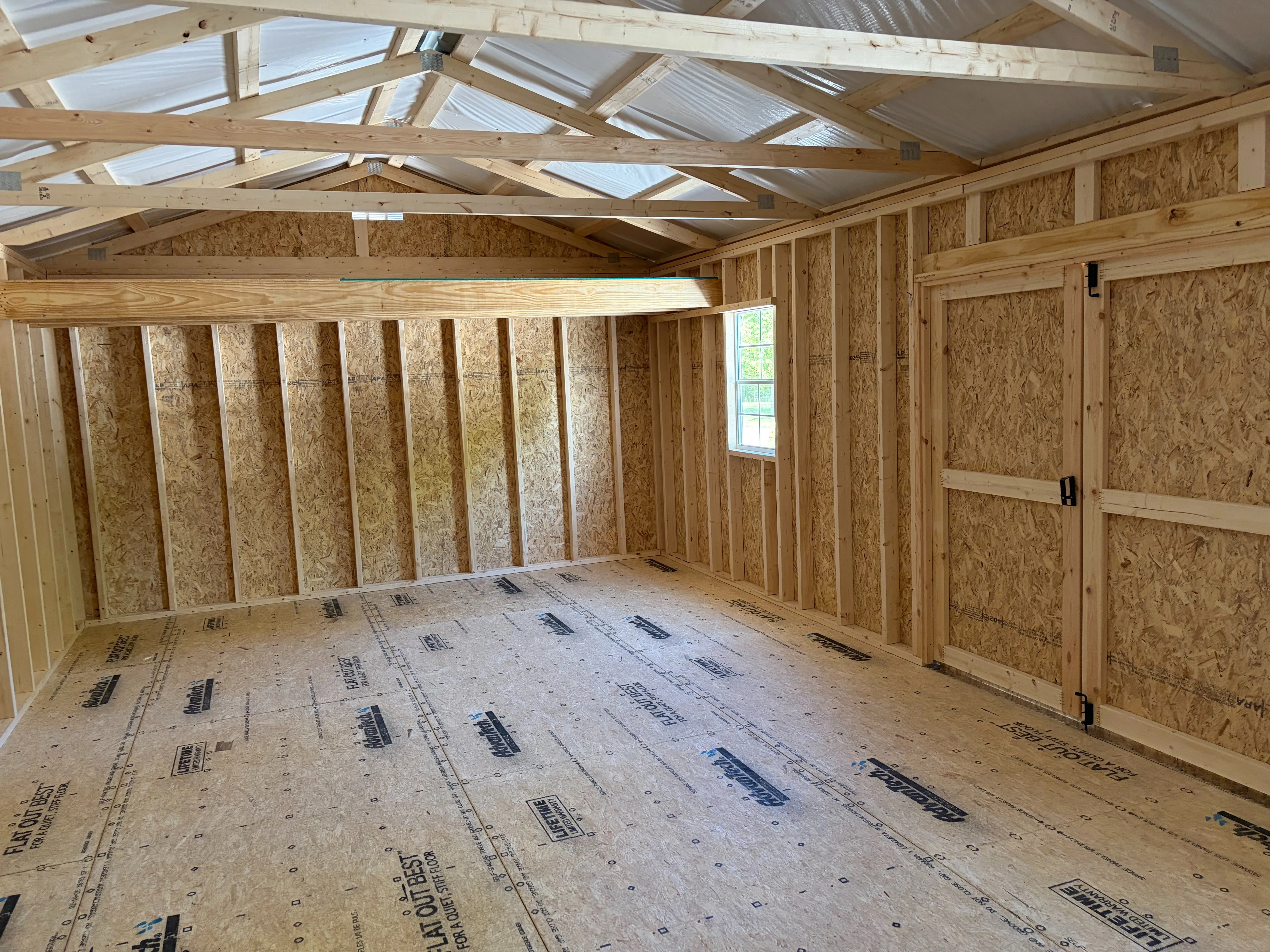 inside a large garage shed that has a loft and a window with the sun shining through the window