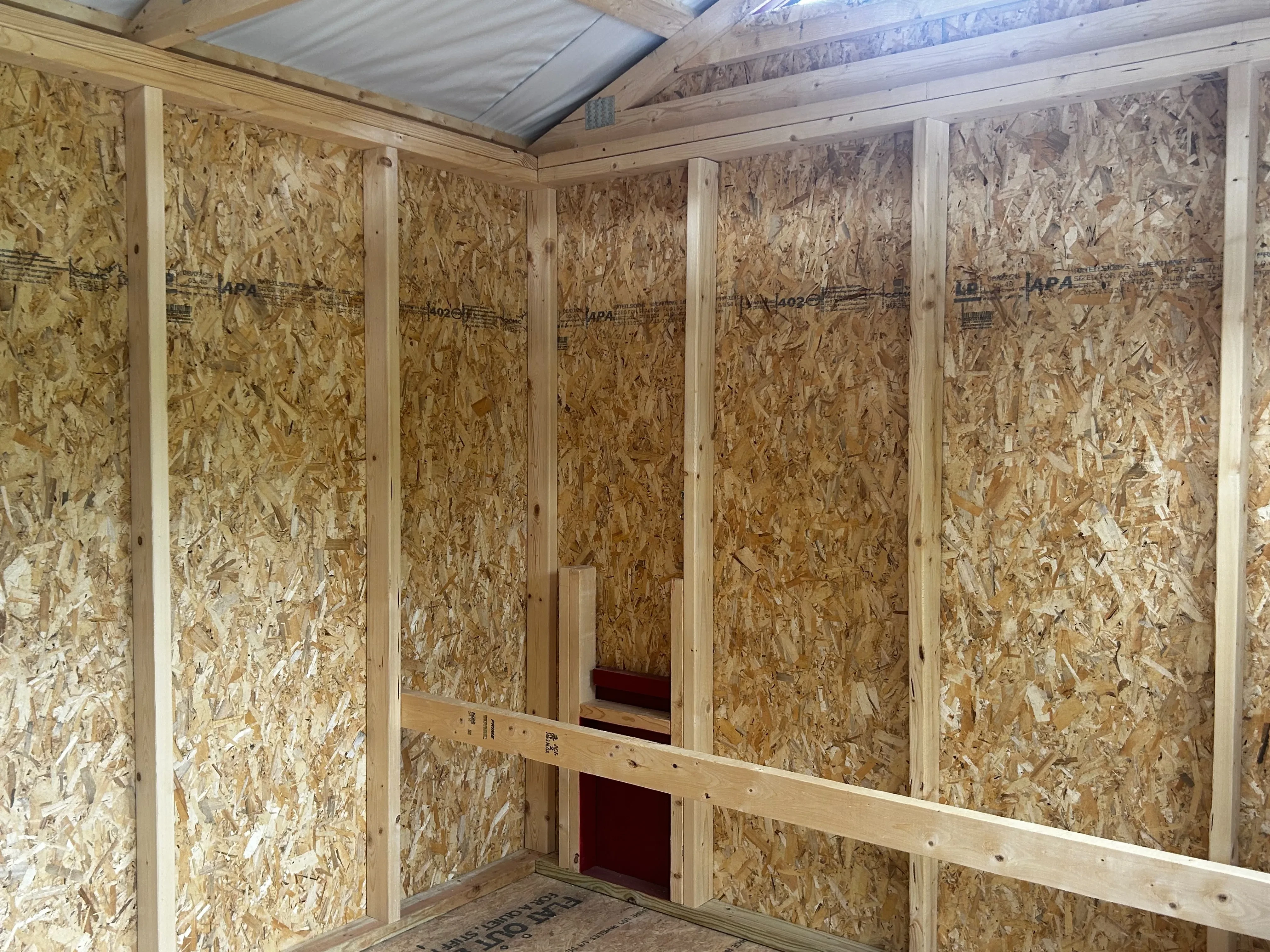 Inside right of a chicken coop showing another roost and exit door