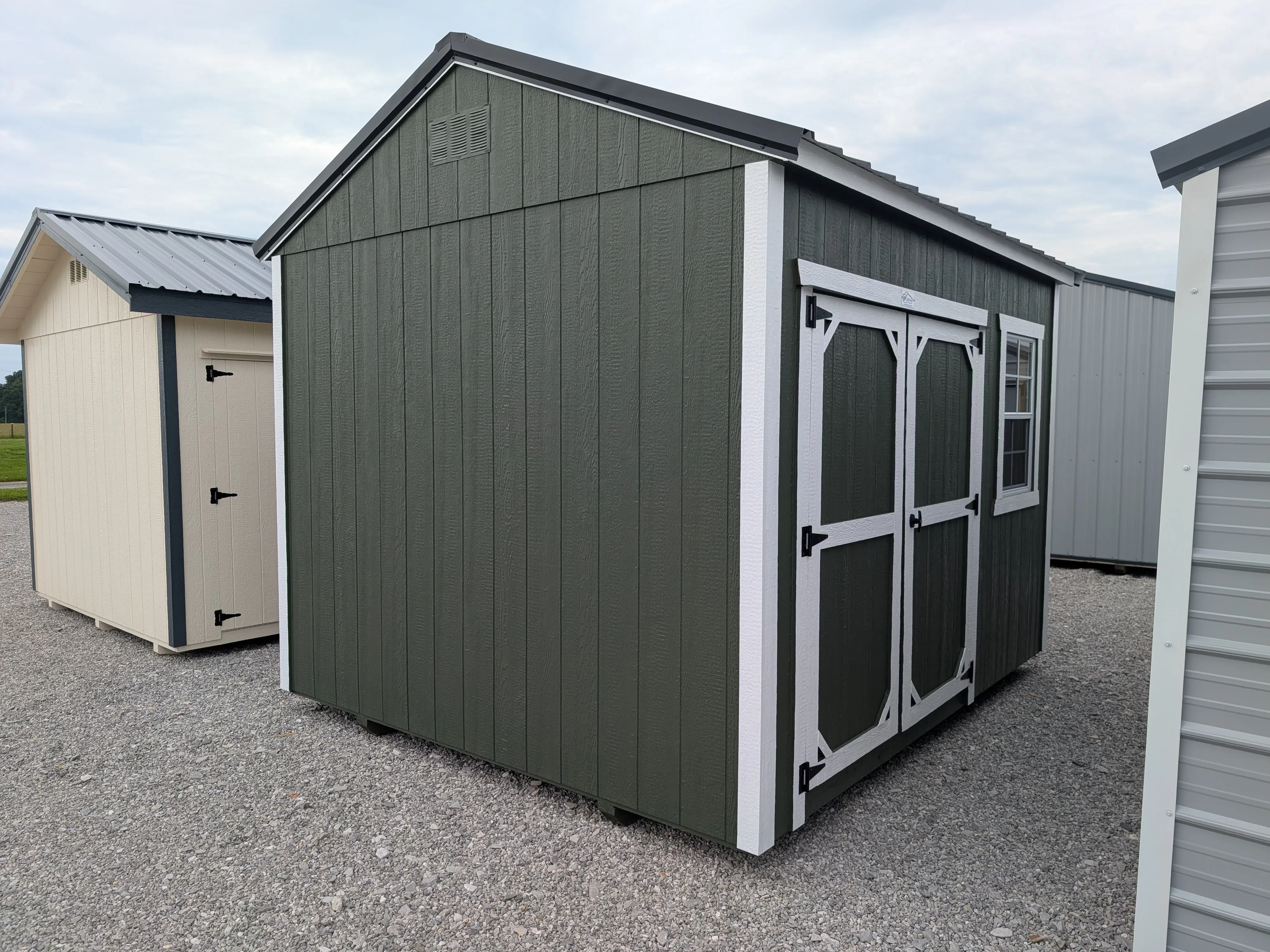a green garden shed with white trim. It has double doors on the front and a 2x3 window next to them.