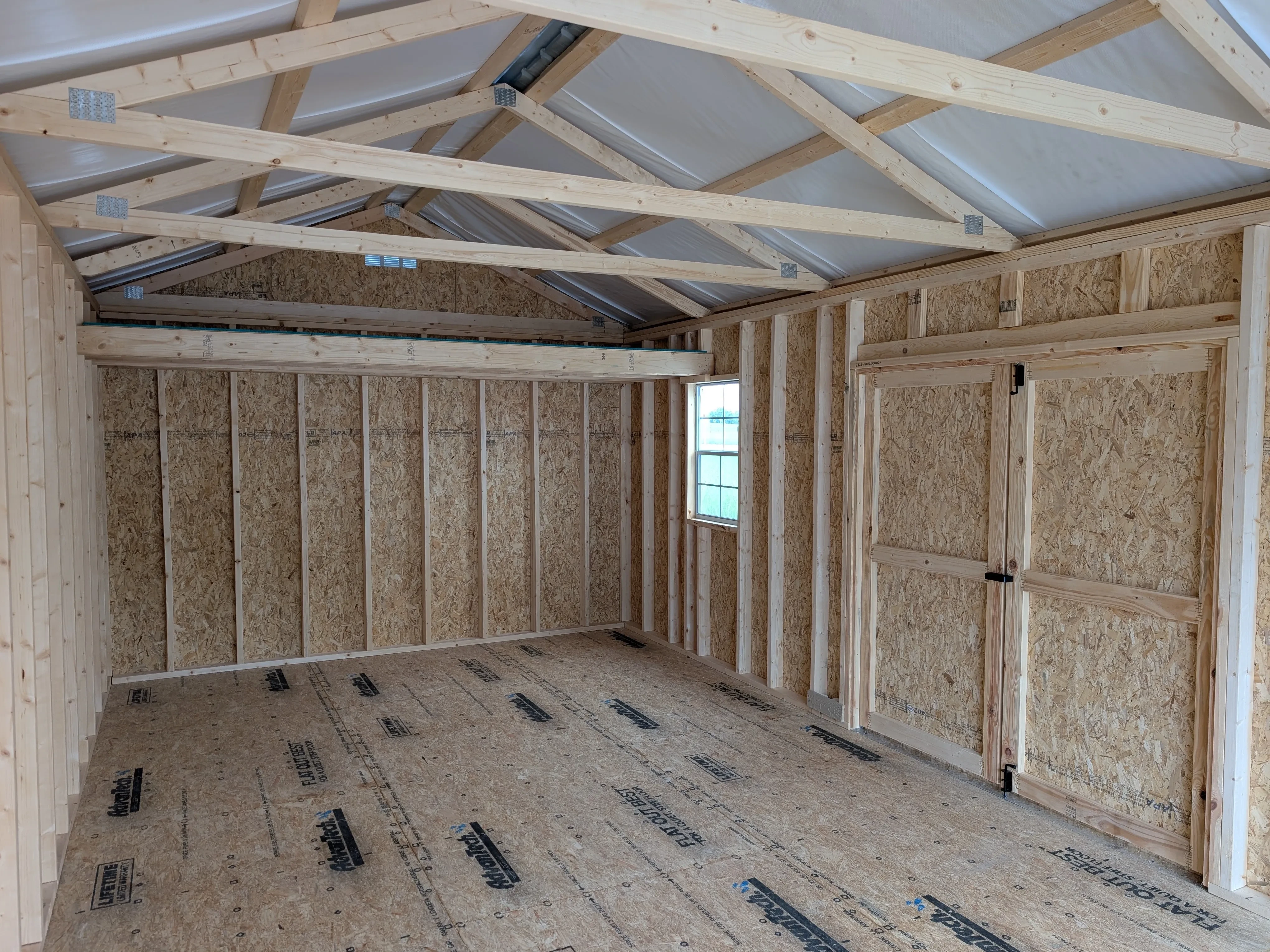 inside a wood portable garage. The right wall has double doors and two 2x3 windows.