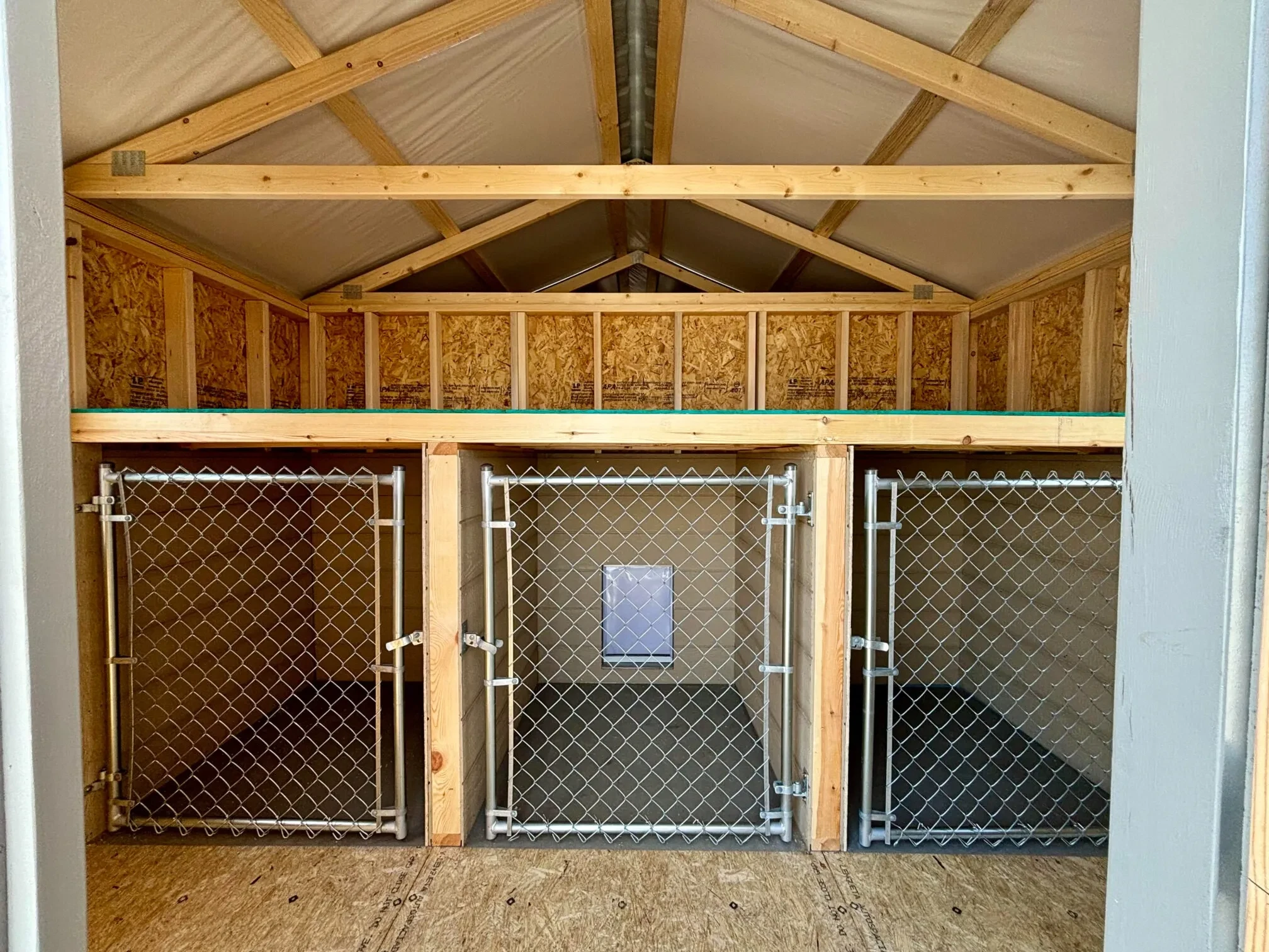 The inside of a dog kennel showing 3 bays and 3 small chain link gates for the dogs to enter