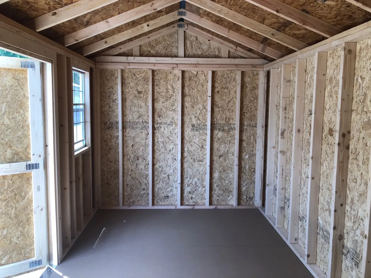 interior of 8x16 garden shed showing the floor and 1 window and open door