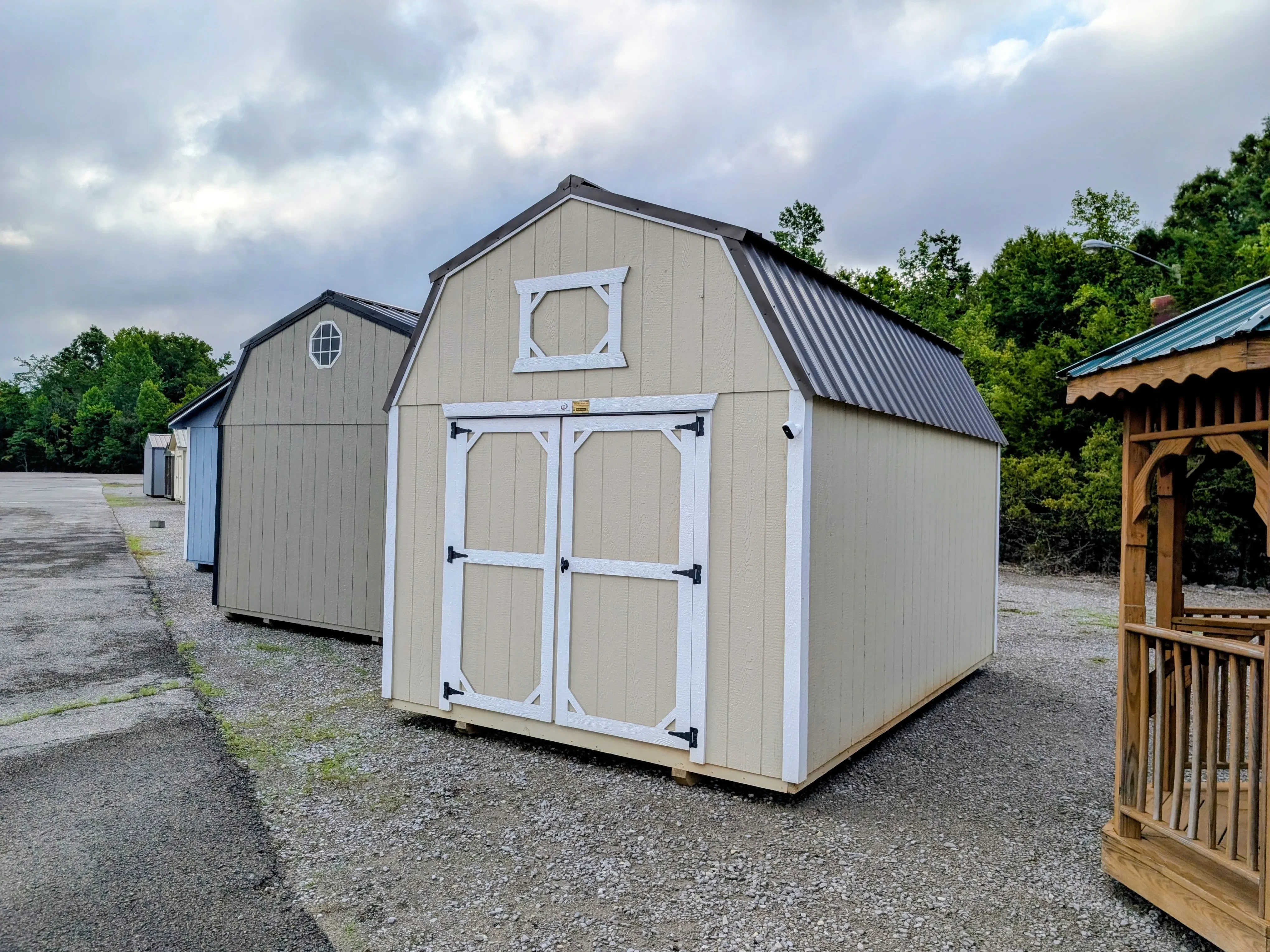 a wooden lofted barn with a burnished slate colored metal roof. It has white trim and double doors in the front
