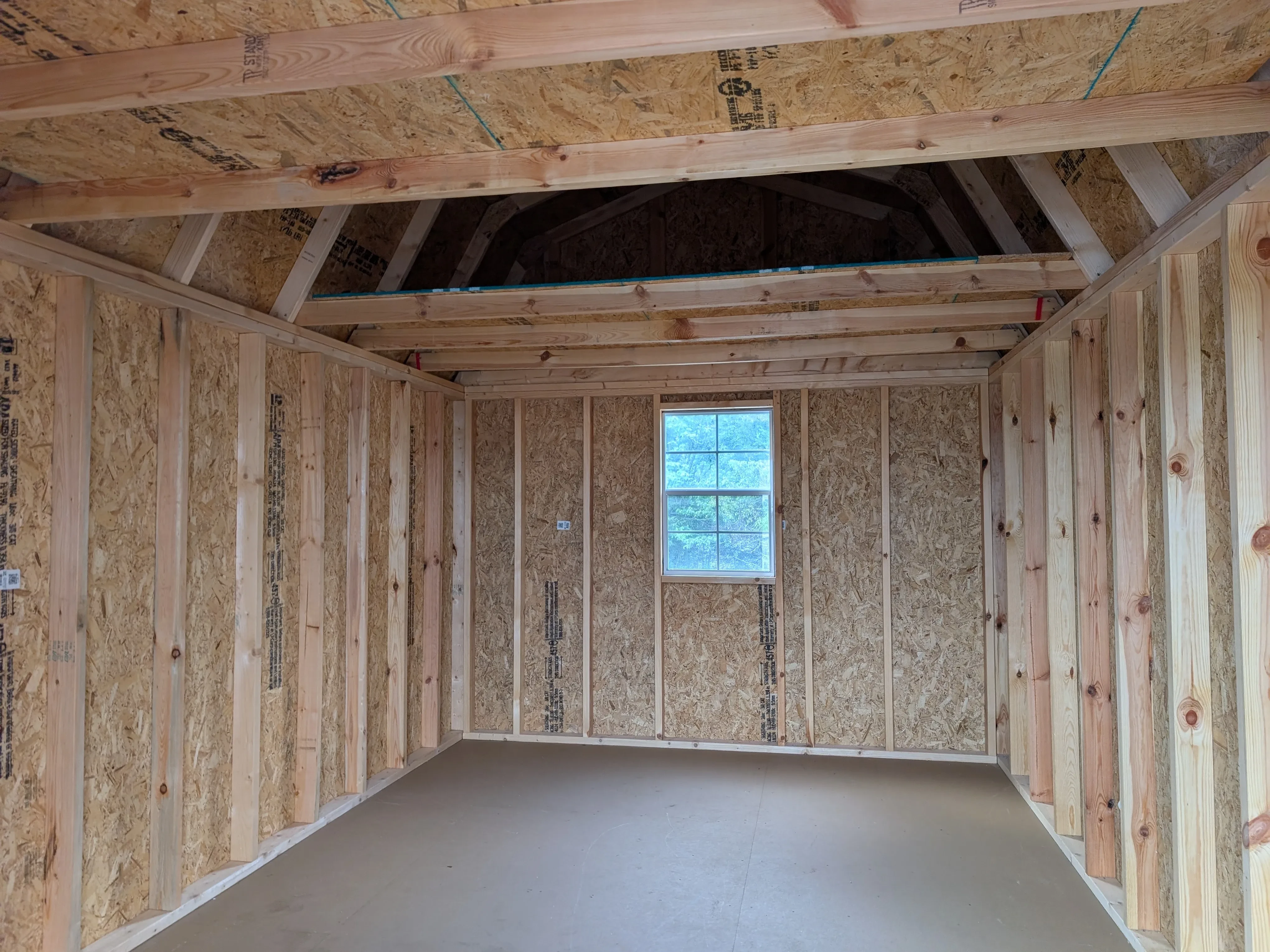 inside a wood lofted barn looking at the back wall. There is a 2x3 window and a loft above the window