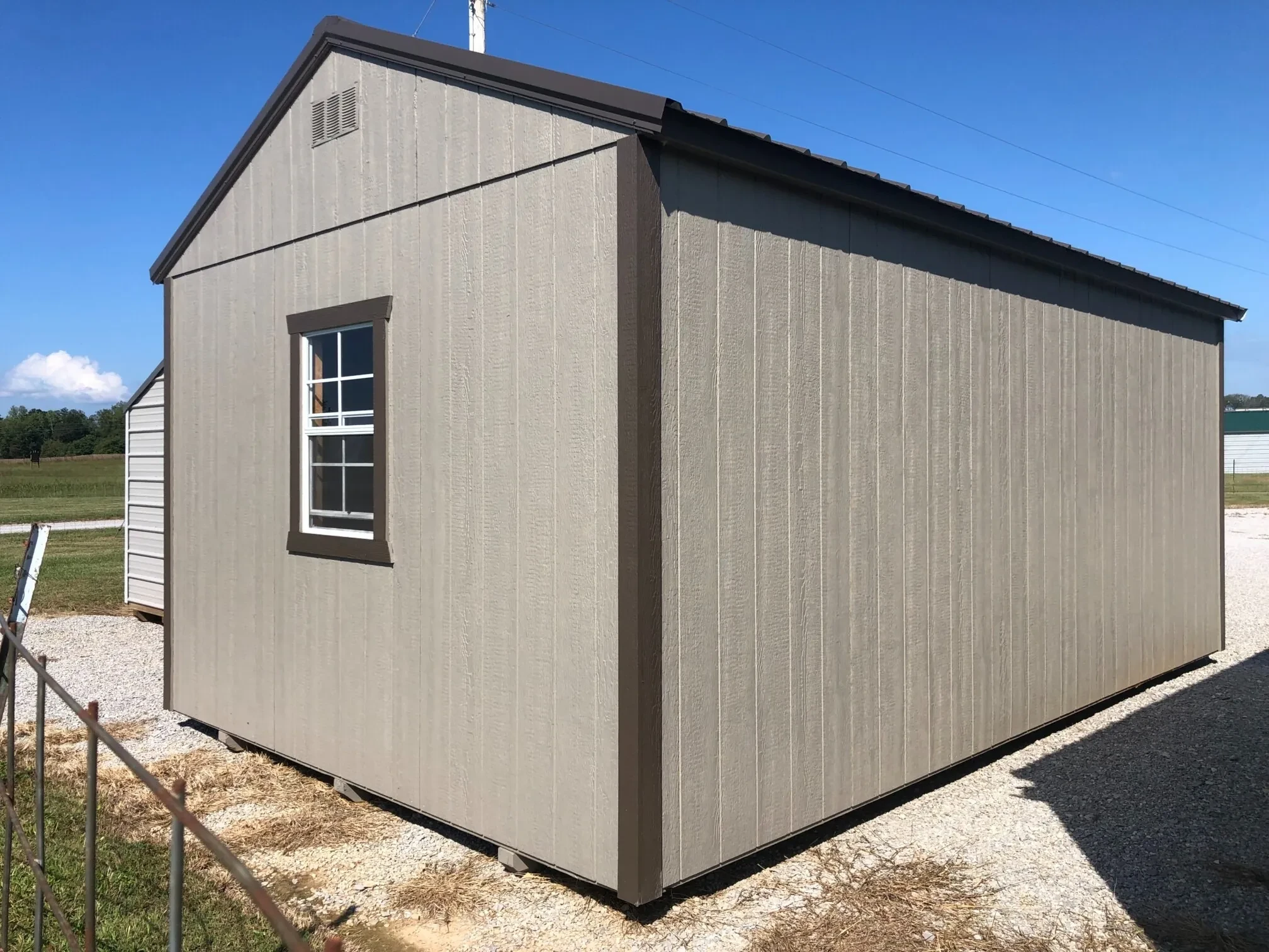 The back corner view of a wood shed showing a window on the back wall