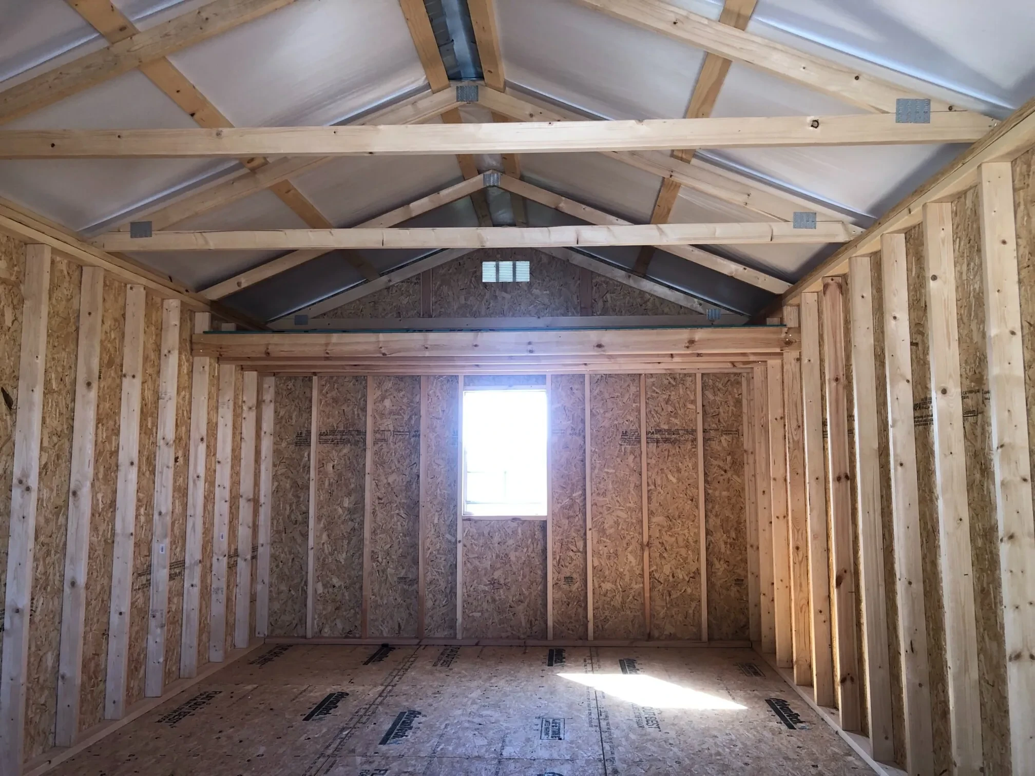 The inside of a shed showing a window and loft along the back wall