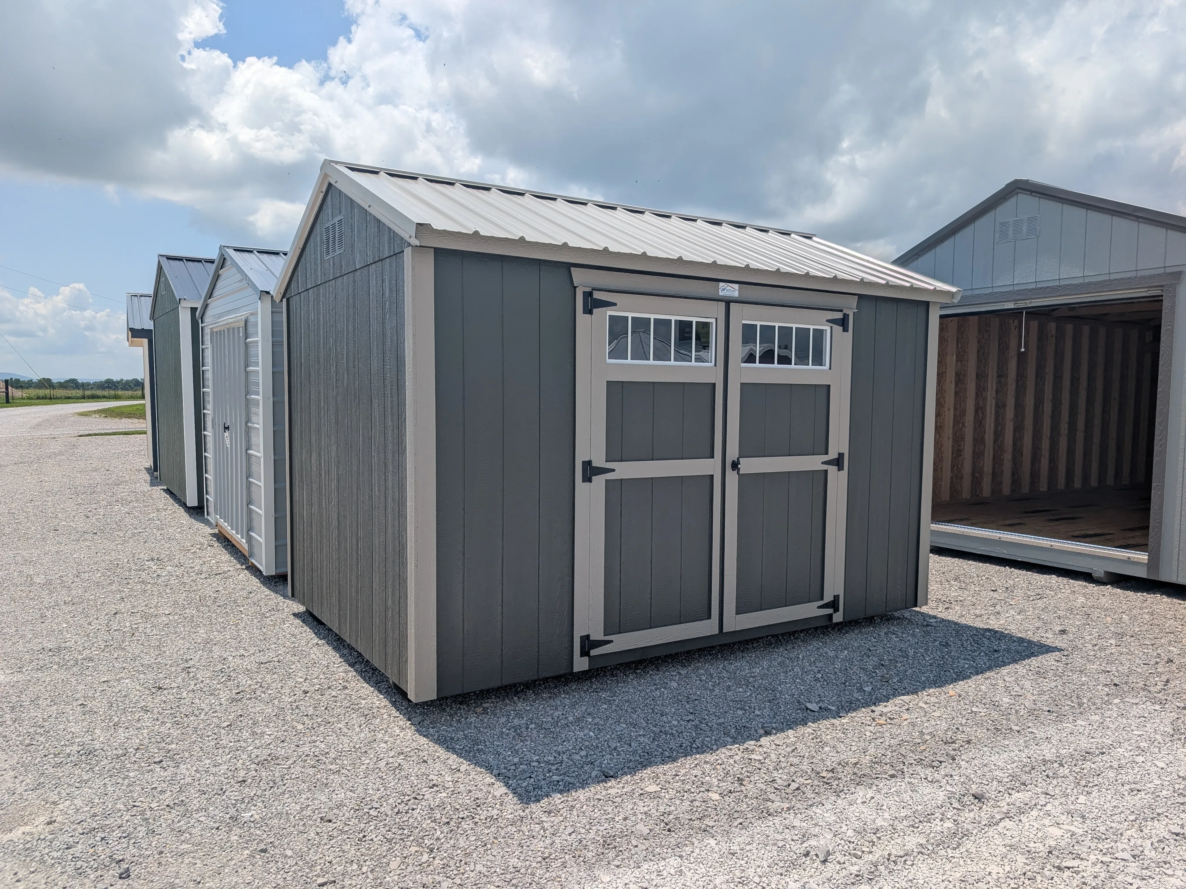 a clay colored garden shed with bronze trim and double doors. There are transom windows in the double doors