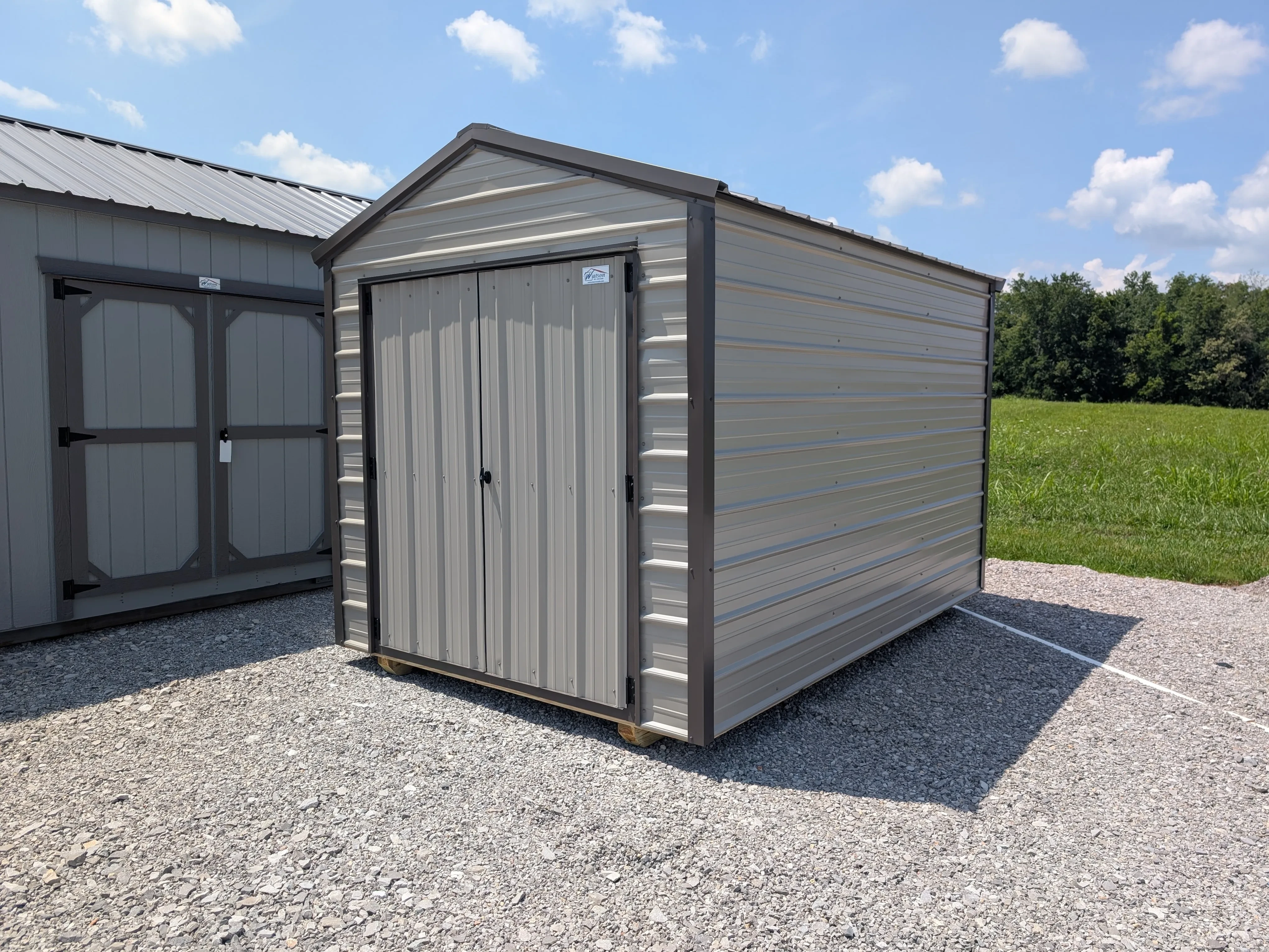 A metal utility shed with double doors in the front. It is a clay color with bronze trim