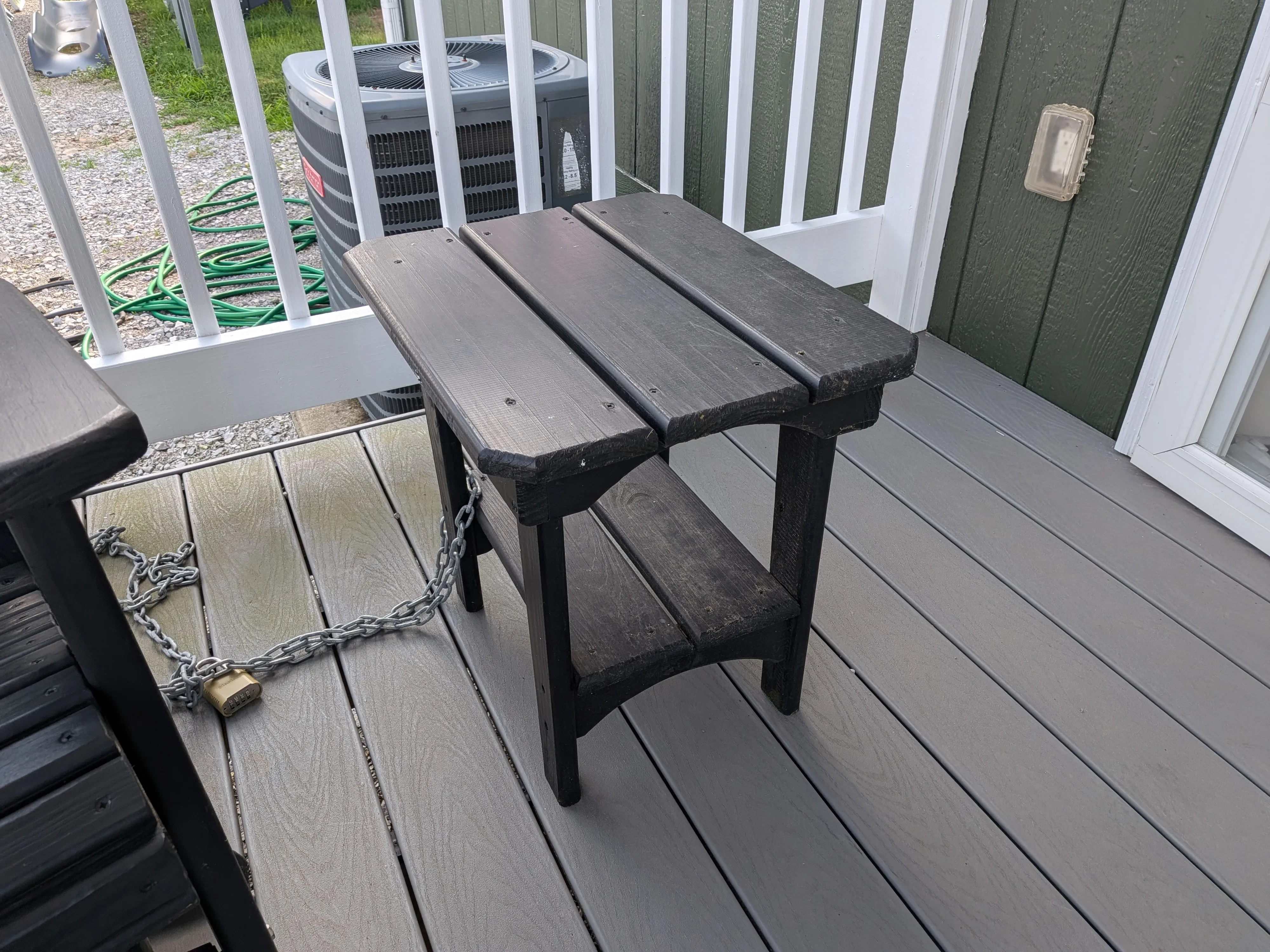 a black wooden end table chained up to a black chair sitting on the porch
