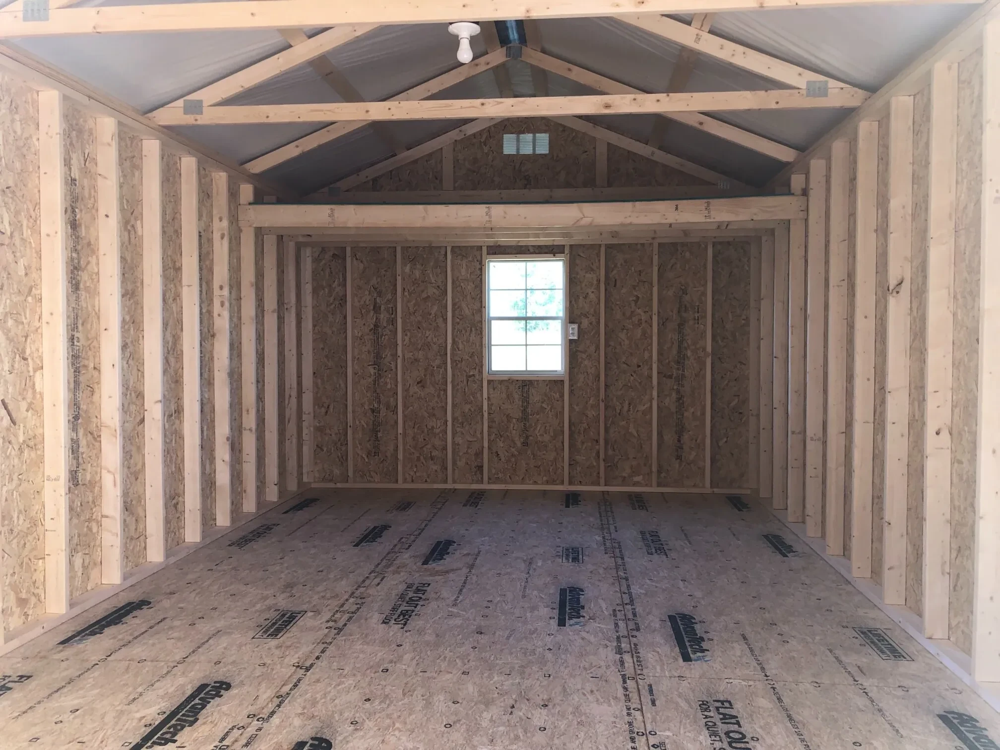 The inside of a shed showing a loft and a window along the back wall and a receptacle next to the window