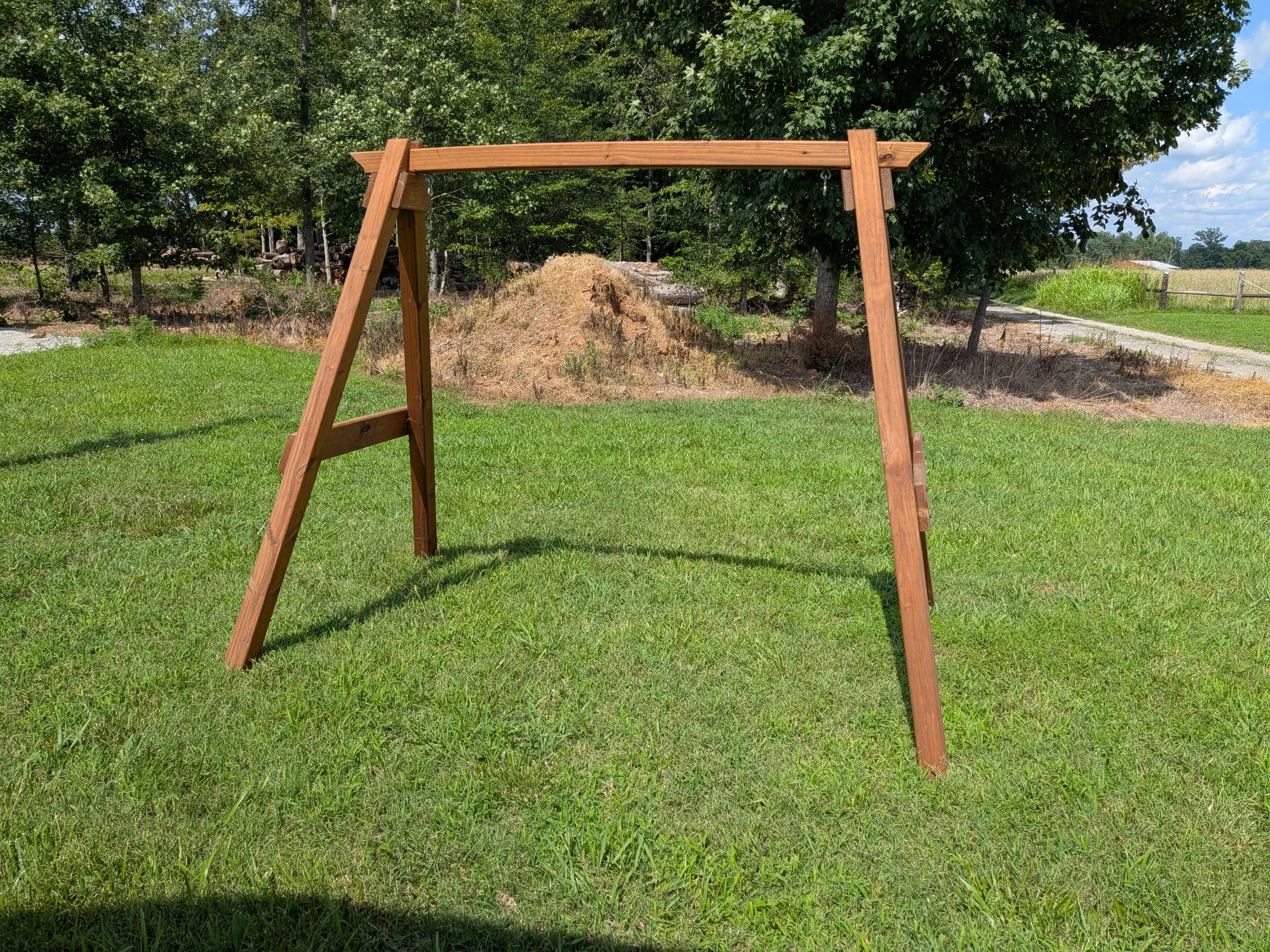 a wooden a-frame structure standing in a field. It is stained and sealed