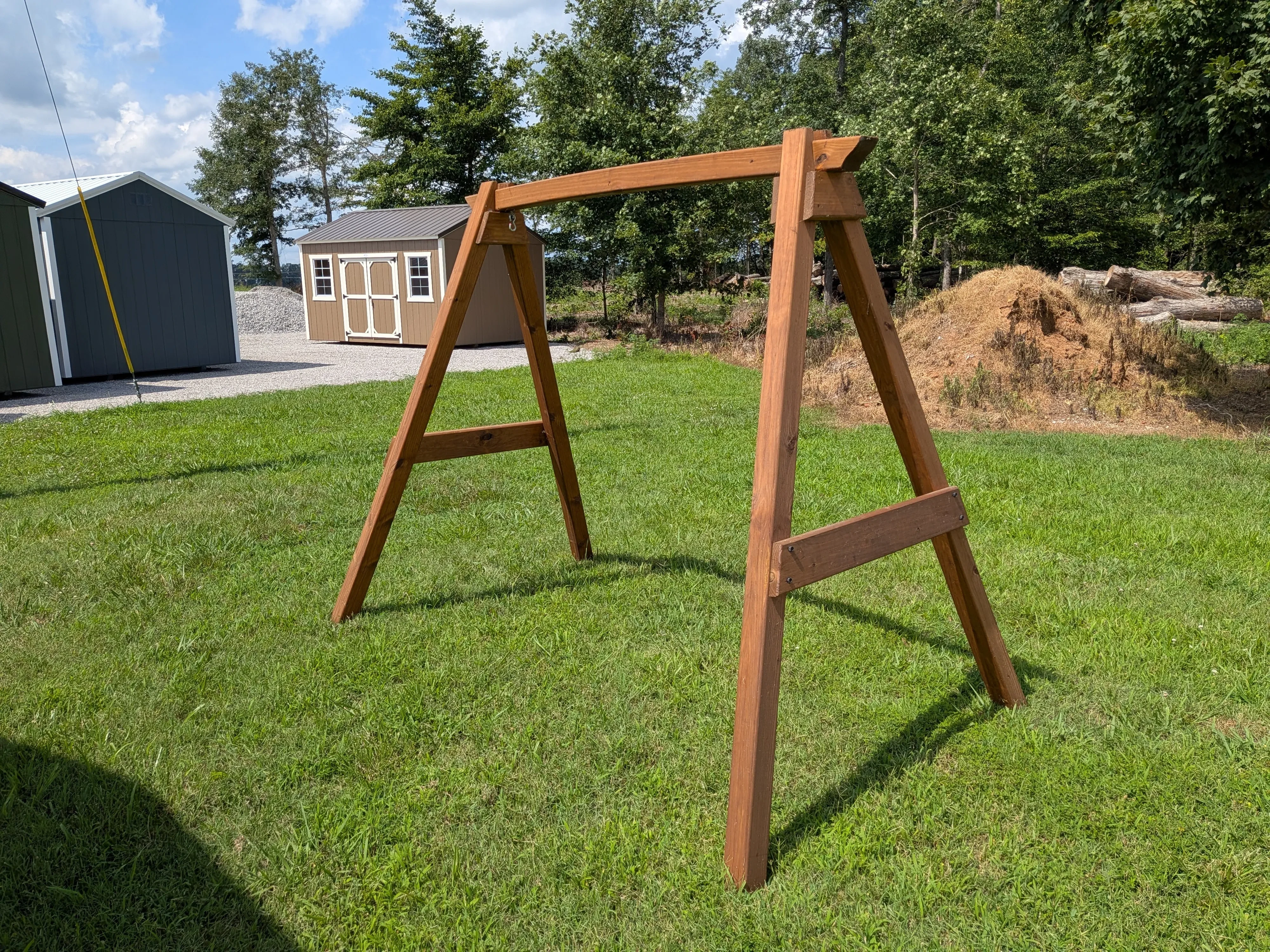 a side view of a wooden a-frame structure sitting in the grass. It is stained and sealed